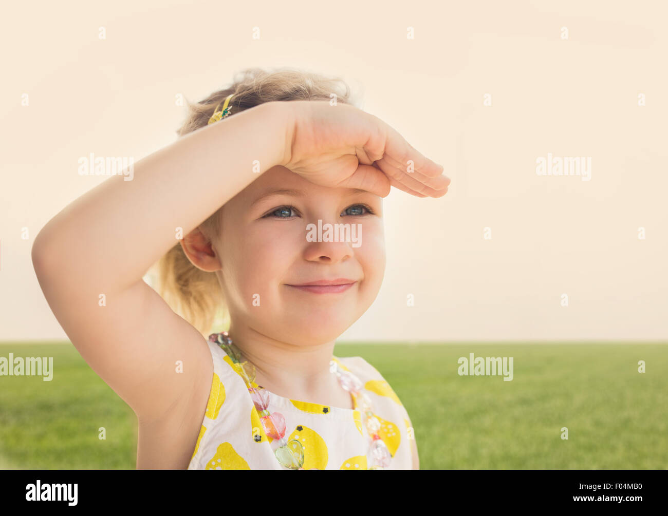 Bambina guardando in avanti con la mano in fronte Foto Stock