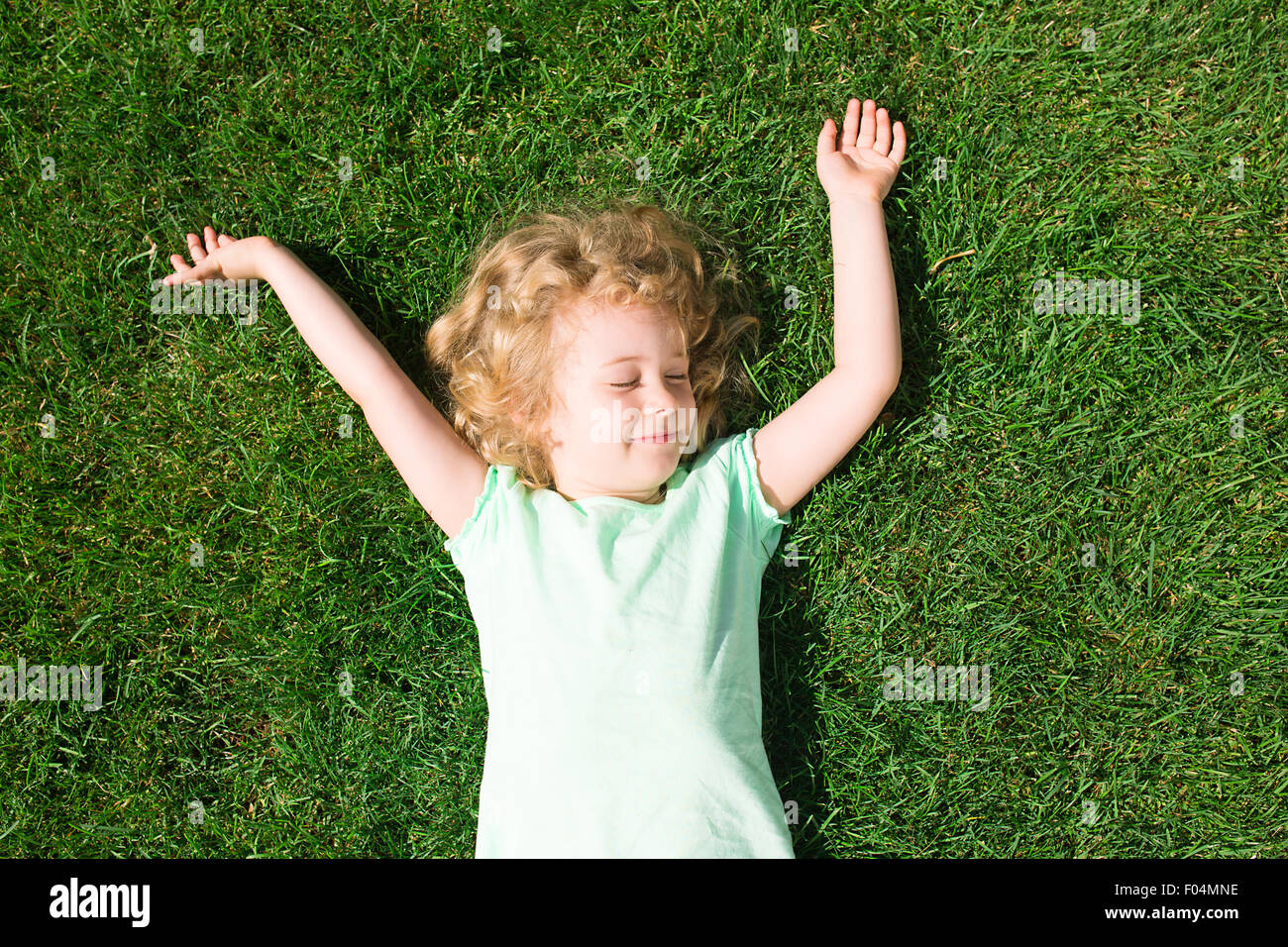 Dreaming adorabile ragazza distesa su erba, vista dall'alto Foto Stock