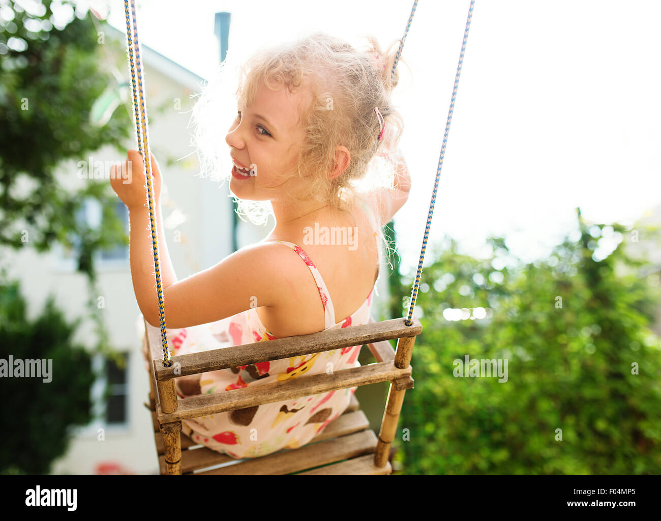 Felice ragazza divertirsi su uno swing sul giorno di estate Foto Stock