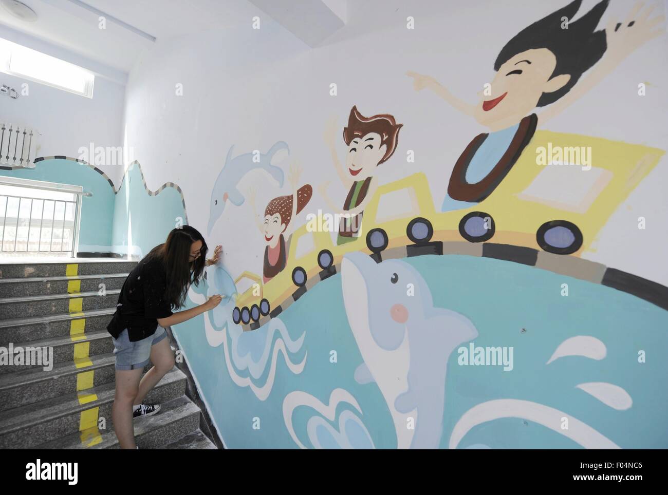 Il Chengde cinese nella provincia di Hebei. Il 6 agosto, 2015. Un volontario di Università Tsinghua dipinge una parete di una scuola primaria alla nella borgata Dayingzi di Chengde County, a nord della Cina di nella provincia di Hebei, il 6 agosto 2015. I volontari di Whitewasher Studio, un club di studenti dell'Università di Tsinghua, dipingere quadri sulle pareti per creare un vivace ambiente scolastico per bambini in aree povere durante l'estate vocazione. © Wang Xiao/Xinhua/Alamy Live News Foto Stock