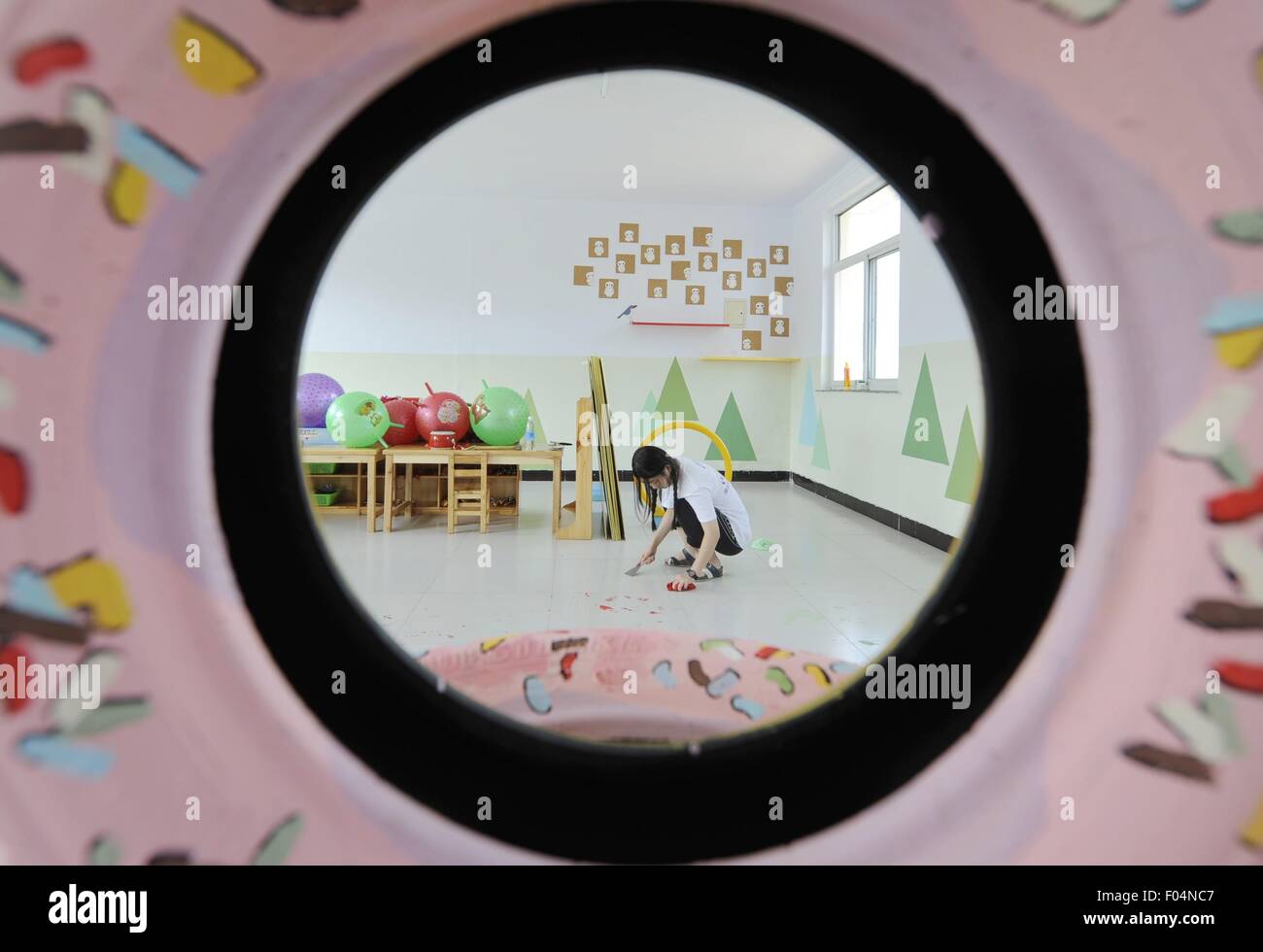 Il Chengde cinese nella provincia di Hebei. Il 6 agosto, 2015. Un volontario di Università Tsinghua pulisce il pavimento di una scuola primaria dopo la verniciatura pareti in Dayingzi township di Chengde County, a nord della Cina di nella provincia di Hebei, il 6 agosto 2015. I volontari di Whitewasher Studio, un club di studenti dell'Università di Tsinghua, dipingere quadri sulle pareti per creare un vivace ambiente scolastico per bambini in aree povere durante l'estate vocazione. © Wang Xiao/Xinhua/Alamy Live News Foto Stock