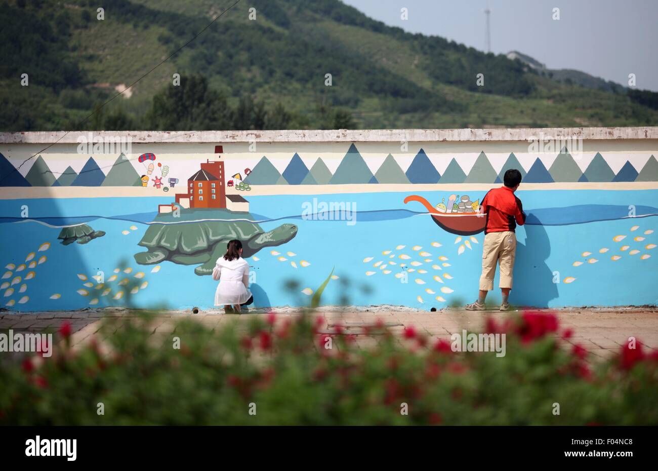 Il Chengde cinese nella provincia di Hebei. Il 6 agosto, 2015. Un volontario di Università Tsinghua dipinge una parete di una scuola primaria alla nella borgata Dayingzi di Chengde County, a nord della Cina di nella provincia di Hebei, il 6 agosto 2015. I volontari di Whitewasher Studio, un club di studenti dell'Università di Tsinghua, dipingere quadri sulle pareti per creare un vivace ambiente scolastico per bambini in aree povere durante l'estate vocazione. © Wang Xiao/Xinhua/Alamy Live News Foto Stock