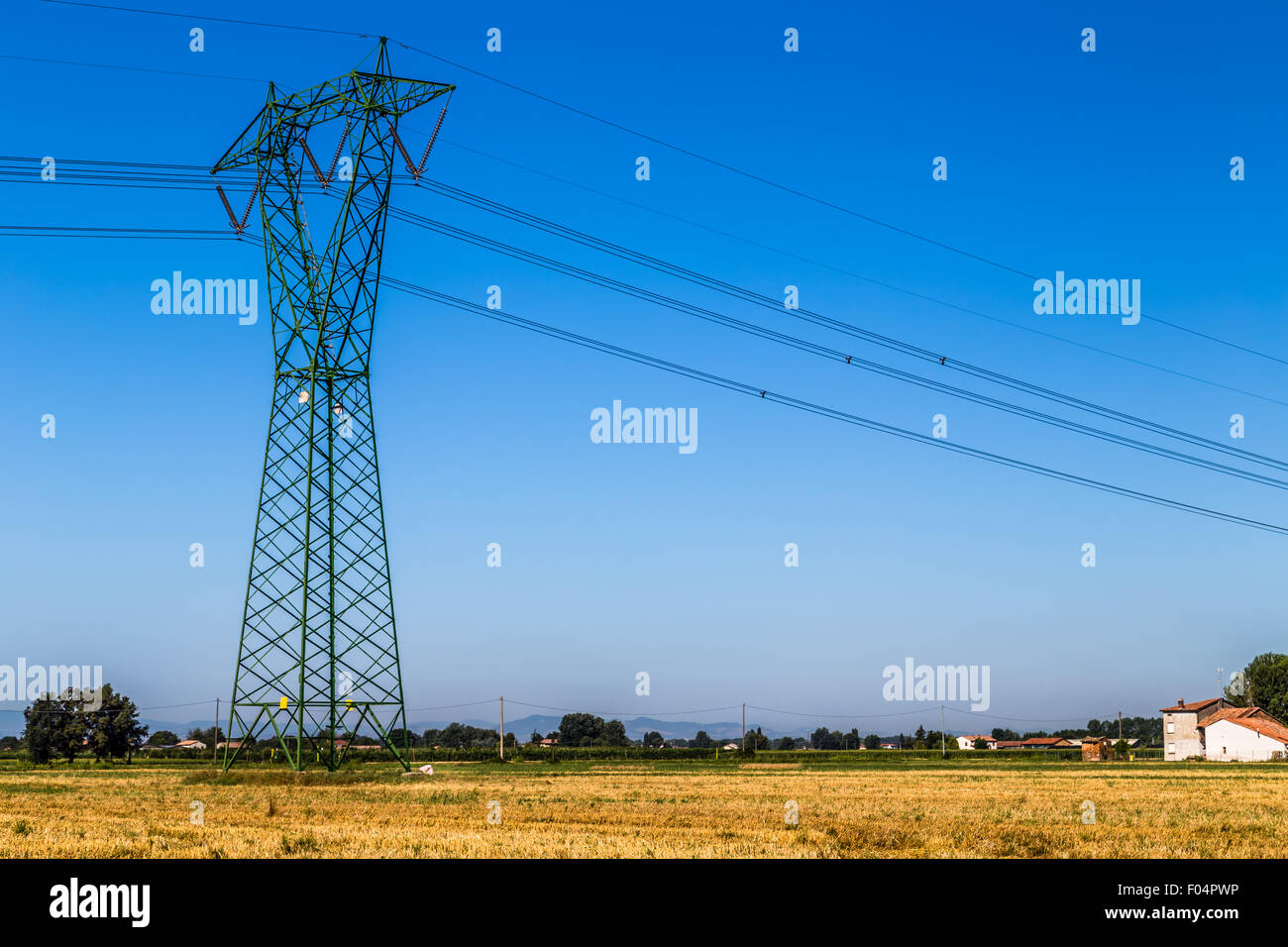 Agricoltura e Industria - Donna vestita in rosa durante la raccolta di prodotti agricoli al di sotto di una tensione elevata pilone gigante Foto Stock