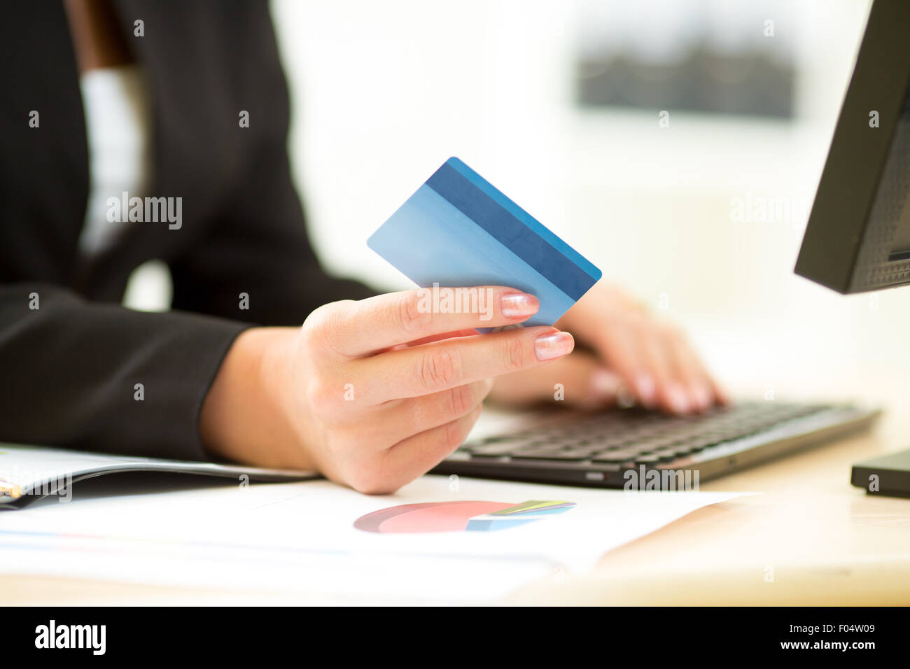 Business donna tenendo la carta di credito in mano e immettendo il codice di protezione utilizzando la tastiera del notebook Foto Stock
