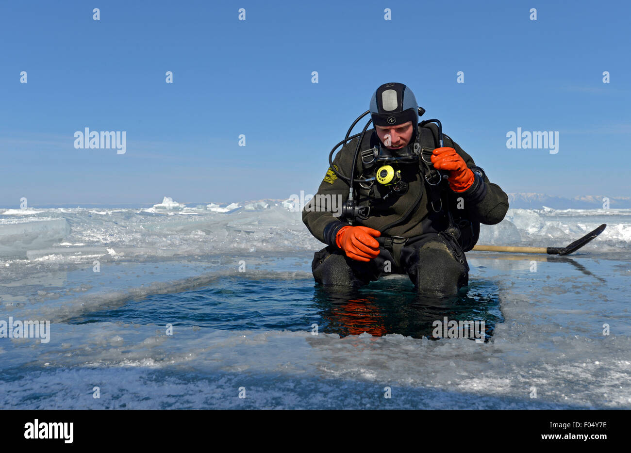 Ice diver con un foro di ghiaccio preparazione per immersione, nel controllo della sua attrezzatura, Lago Baikal, Siberia, Russia Foto Stock