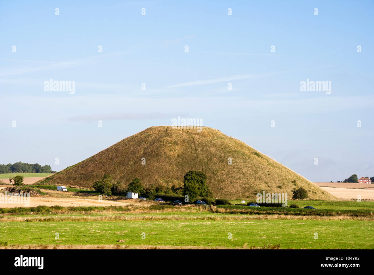 Distante colpo di Silbury Hill, man-made tumulo neolitico in Inghilterra. Un alto 40 metri artificiali del tumulo di erba in piedi di altezza relativamente piatto paesaggio. Foto Stock