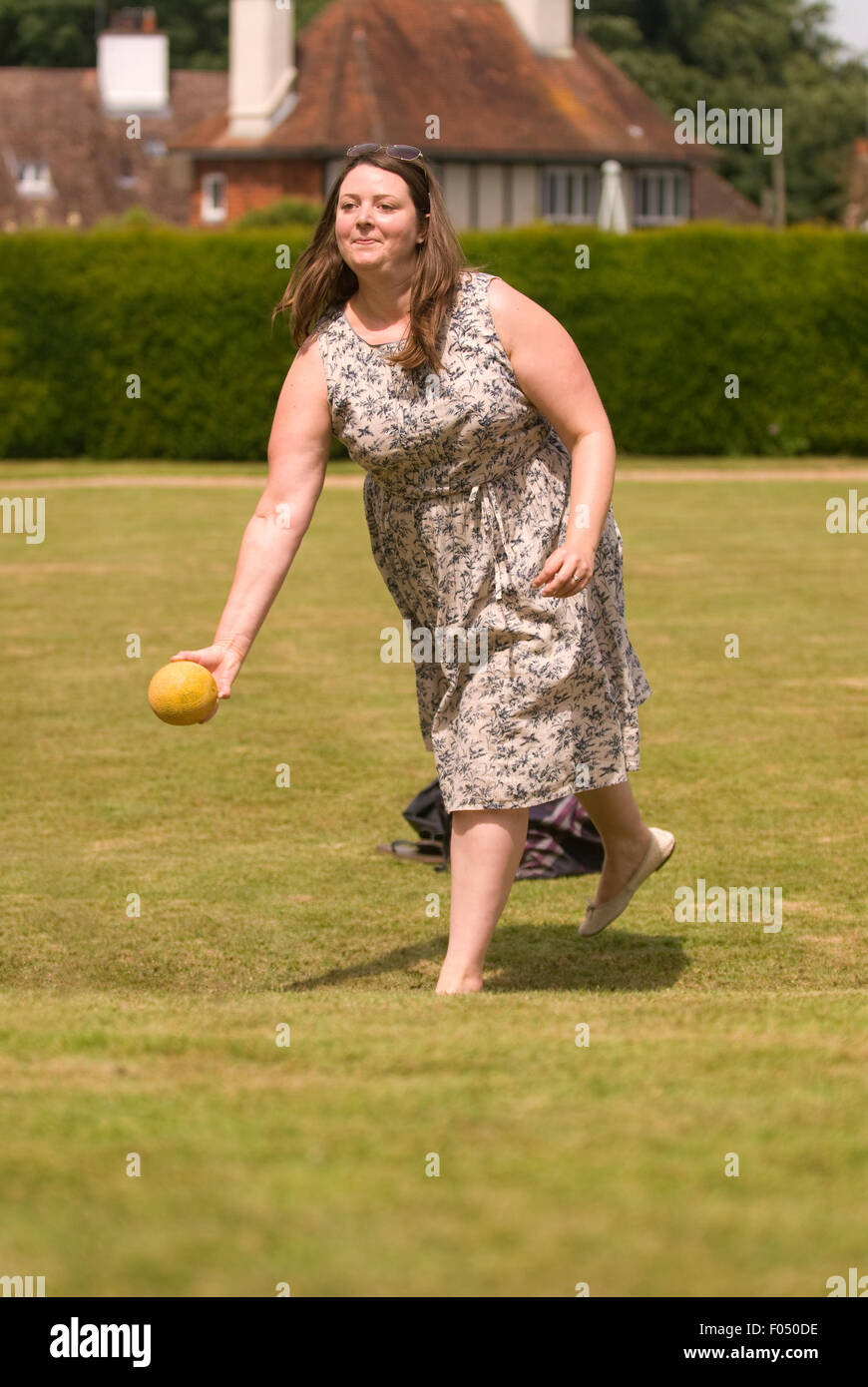 Donna che gioca il melone bowling in un paese equo, Selborne, Hampshire, Regno Unito. Foto Stock
