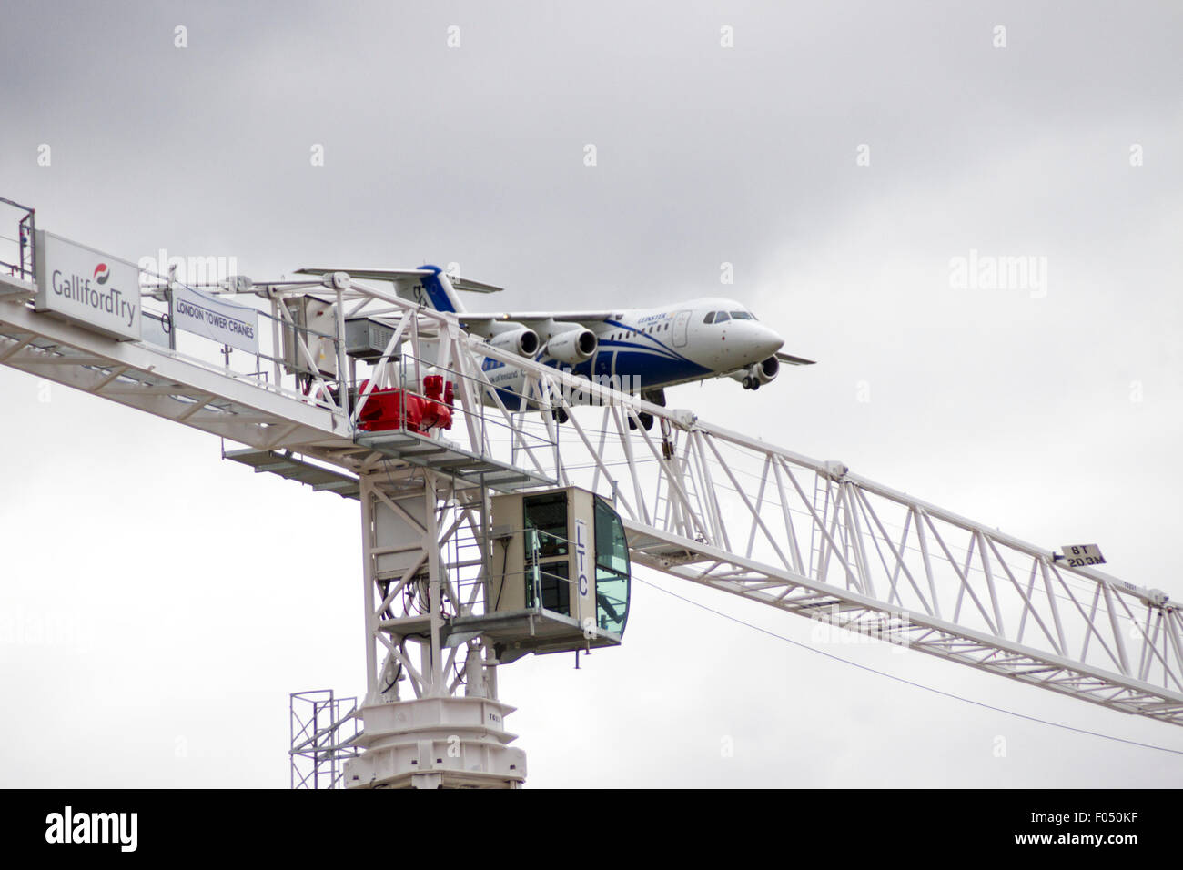 Cityjet Dornier 328-110 in atterraggio a City Airport London dietro di gru a torre galeoni a raggiungere lo sviluppo, Docklands Foto Stock
