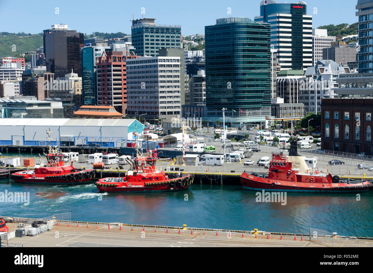 Rimorchiatore rosso imbarcazioni al porto, edifici per uffici e il CBD dietro, Wellington, Isola del nord, Nuova Zelanda Foto Stock