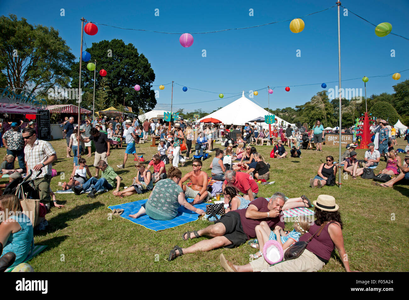 Le famiglie delle parti in estate sole a chioschi e tabelloni elettronici al porto Eliot Festival Cornovaglia Foto Stock