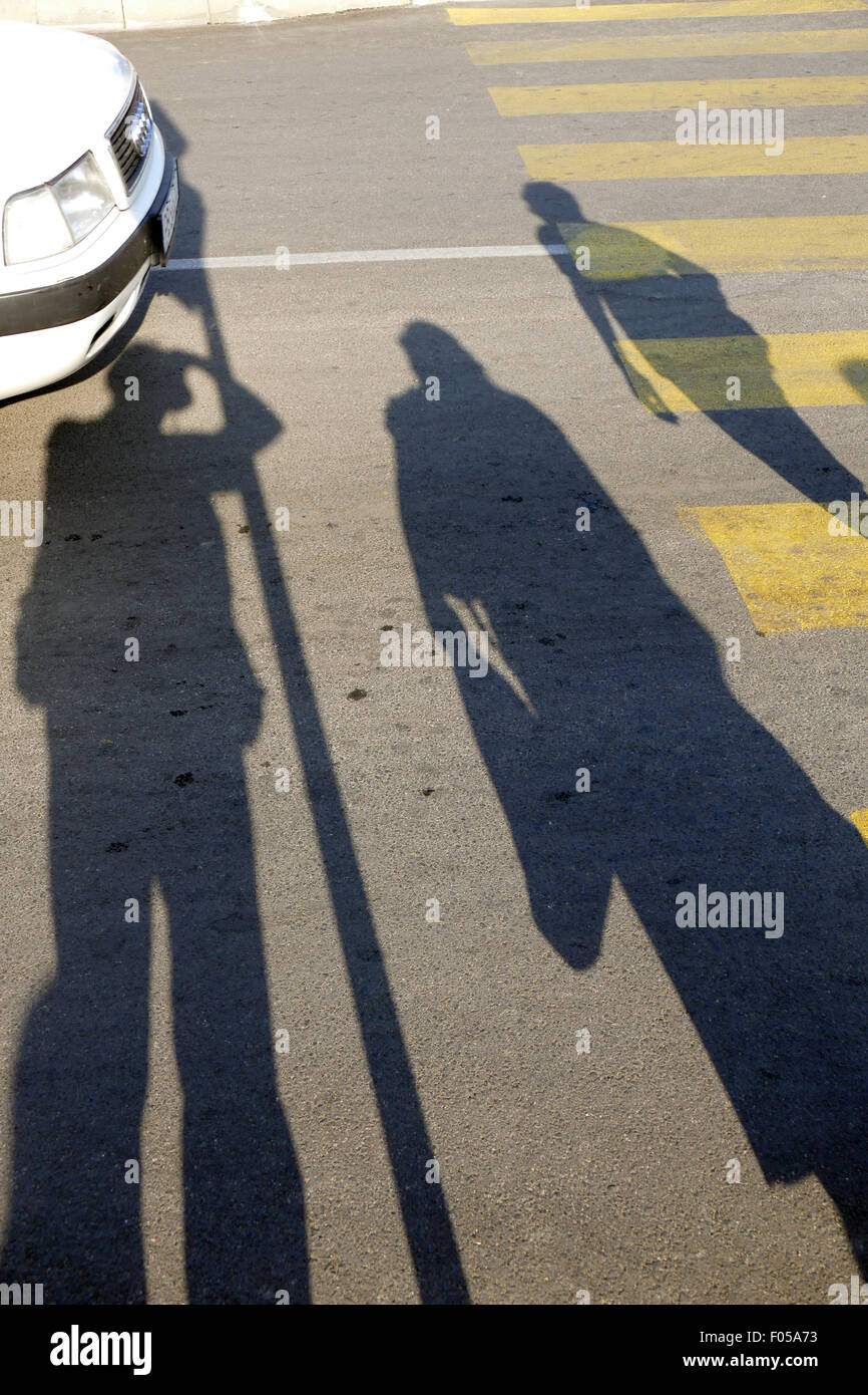 Le ombre dei pedoni in attesa in corrispondenza di un passaggio pedonale. Foto Stock