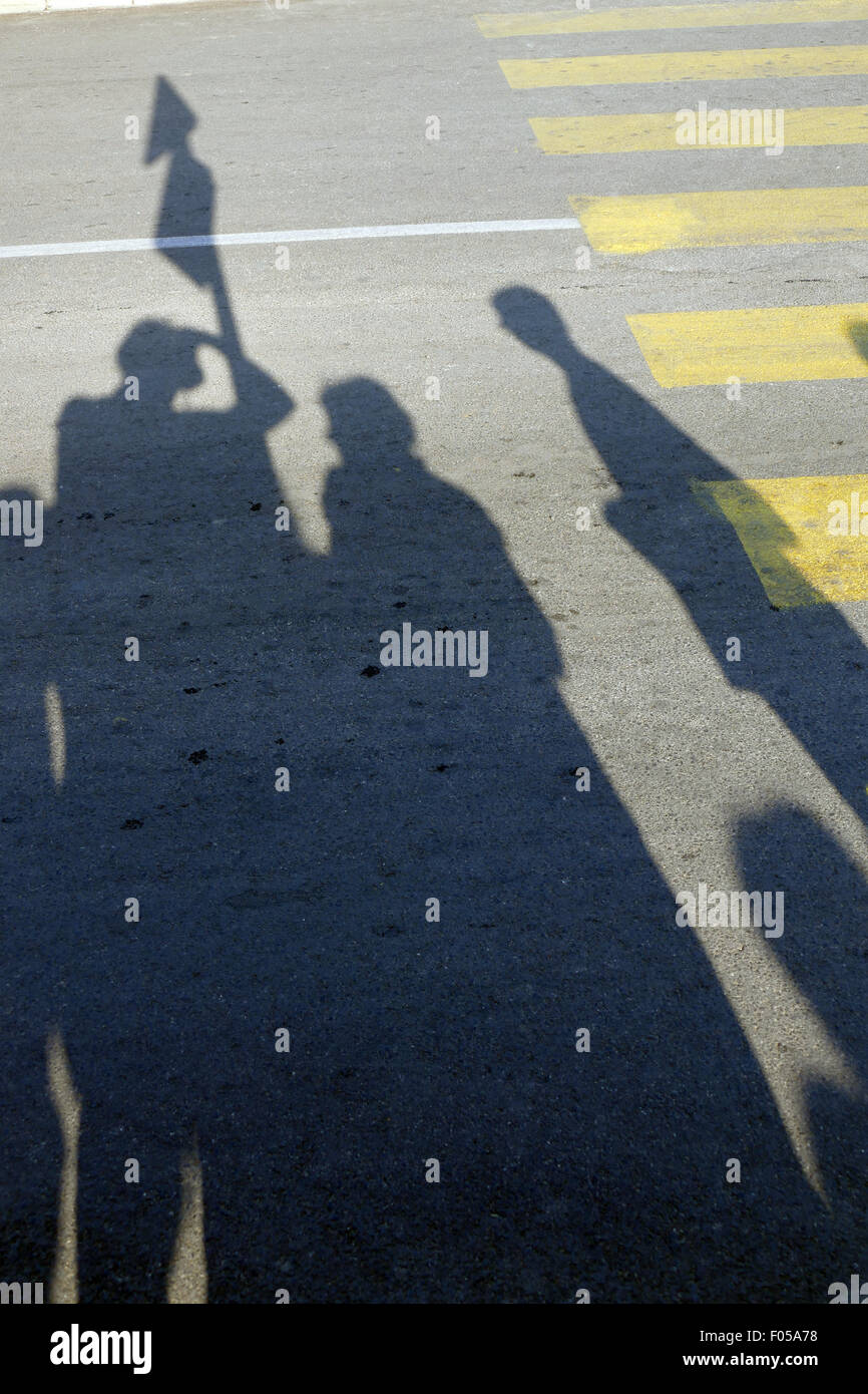 Le ombre dei pedoni in attesa in corrispondenza di un passaggio pedonale. Foto Stock