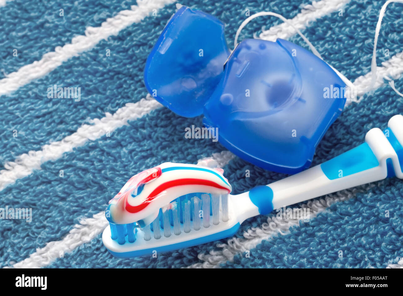 Il filo interdentale e uno spazzolino da denti blu su un asciugamano Foto Stock