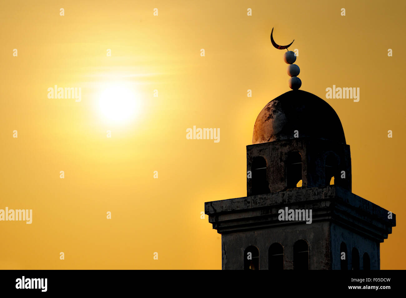 Torre della moschea illuminata dal sole che sorge Foto Stock
