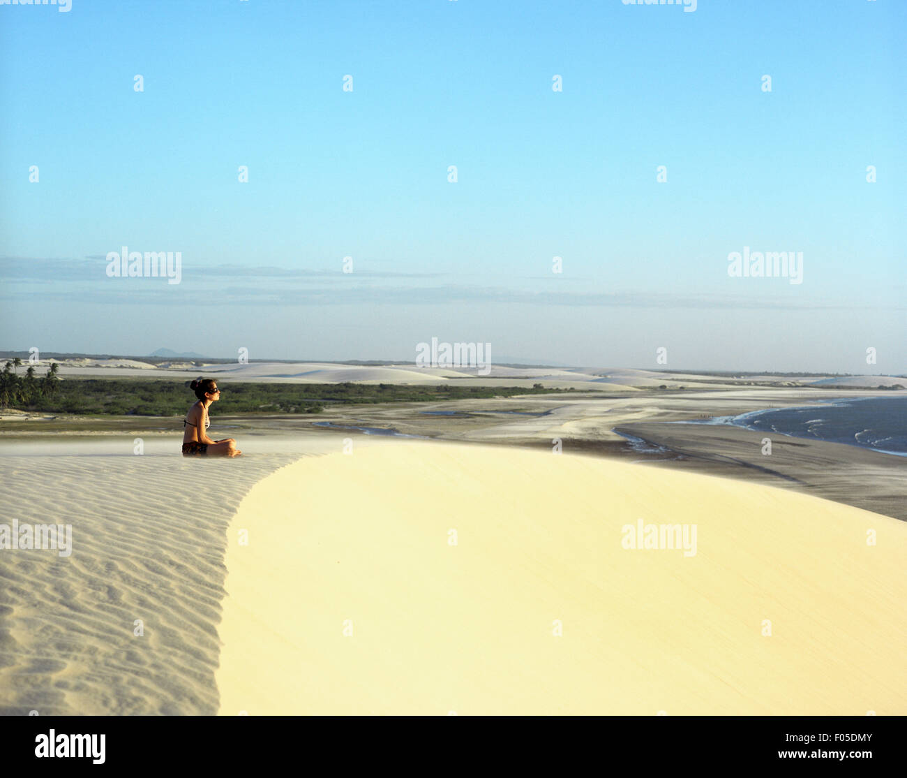 Una giovane donna medita a duna del tramonto. Jericoacoara, Brasile Foto Stock