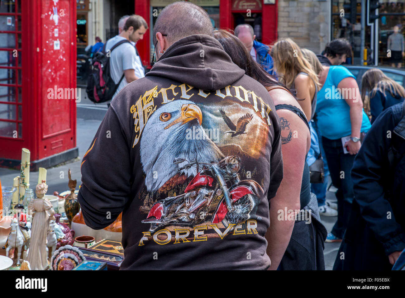 Il cliente indossa una felpa con cappuccio dotato di un aquila calva, una moto navigando in una fase di stallo nel Grassmarket. Foto Stock