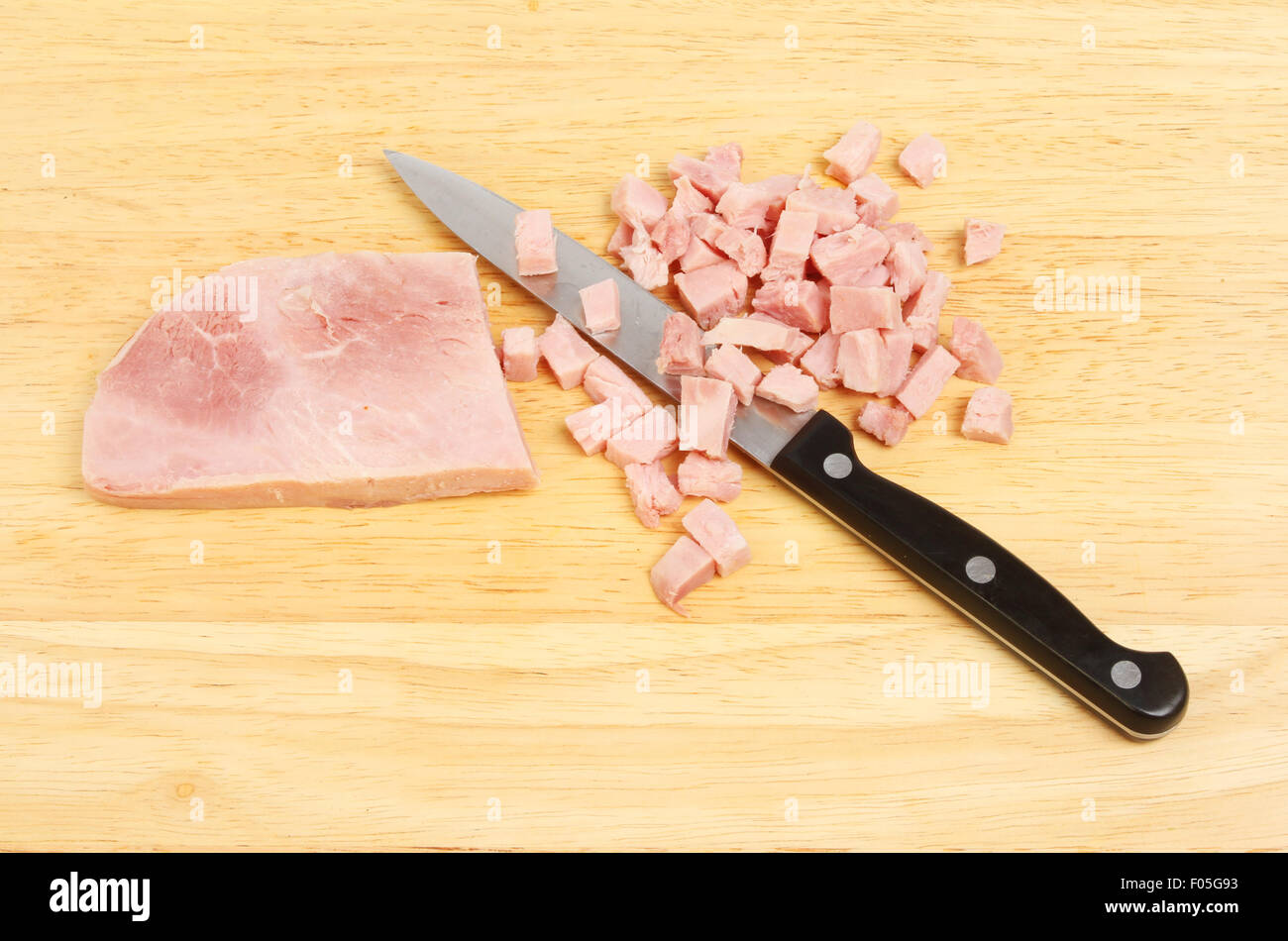 Il prosciutto tritato con un coltello su un pannello di legno Foto Stock