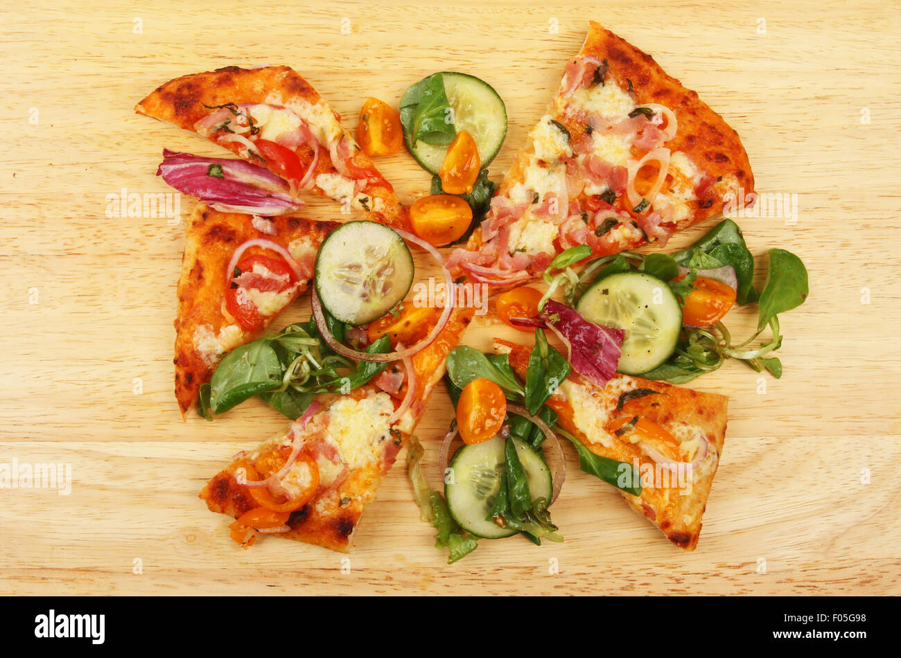 Fette di pizza e insalate condite su una tavola di legno Foto Stock