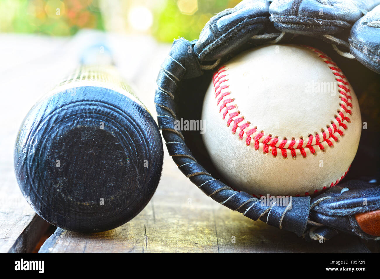 Vecchio bat e la sfera all'interno di un guanto in appoggio su un tavolo di legno Foto Stock