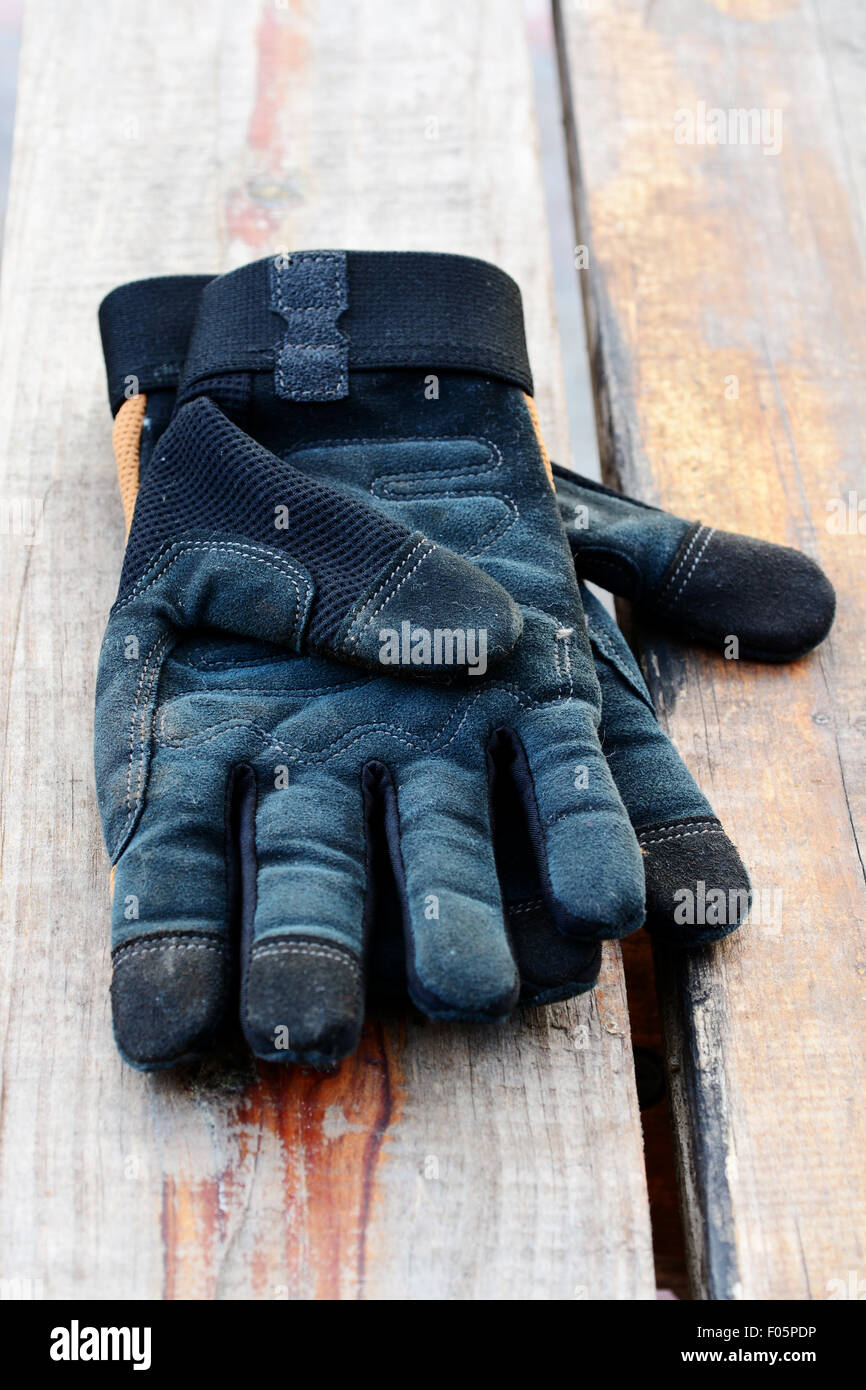 Coppia di lavoro nero Guanti in pelle su una tavola di legno Foto Stock