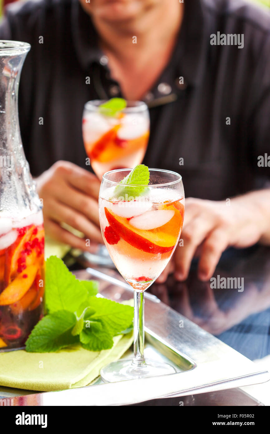 L'uomo bianco potabile sangria. La sangria bianca con frutti e bacche. Foto Stock