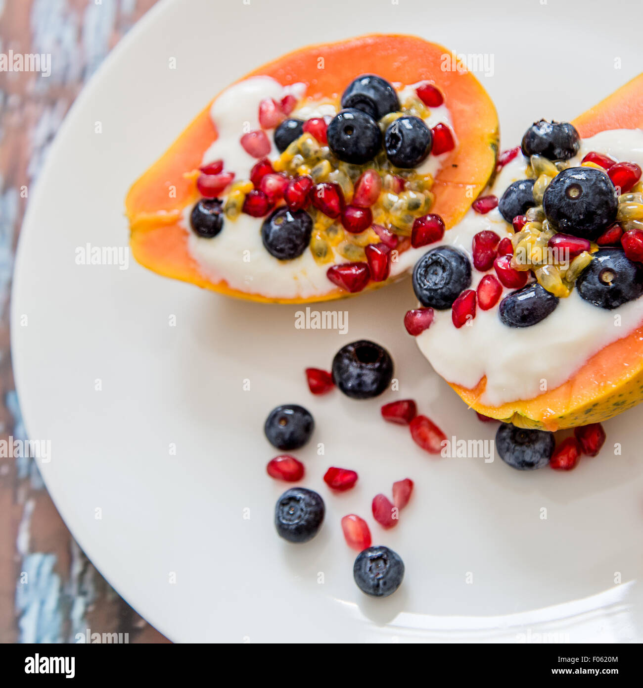 La papaia con soia naturale yogurt e frutti di bosco freschi, leggera e sana colazione, papaia, mirtilli, frutto della passione, melograno Foto Stock