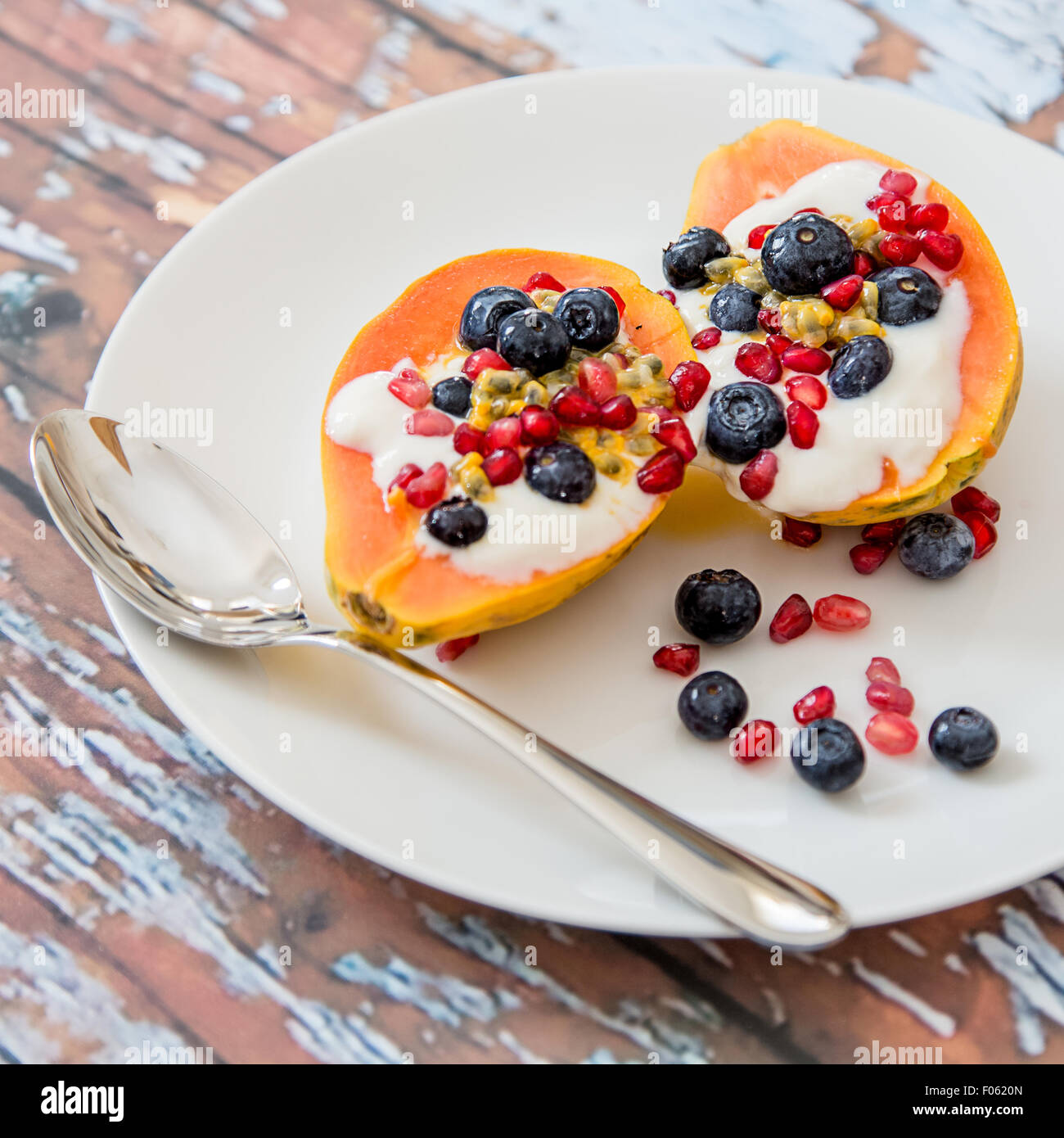 La papaia con soia naturale yogurt e frutti di bosco freschi, leggera e sana colazione, papaia, mirtilli, frutto della passione, melograno Foto Stock