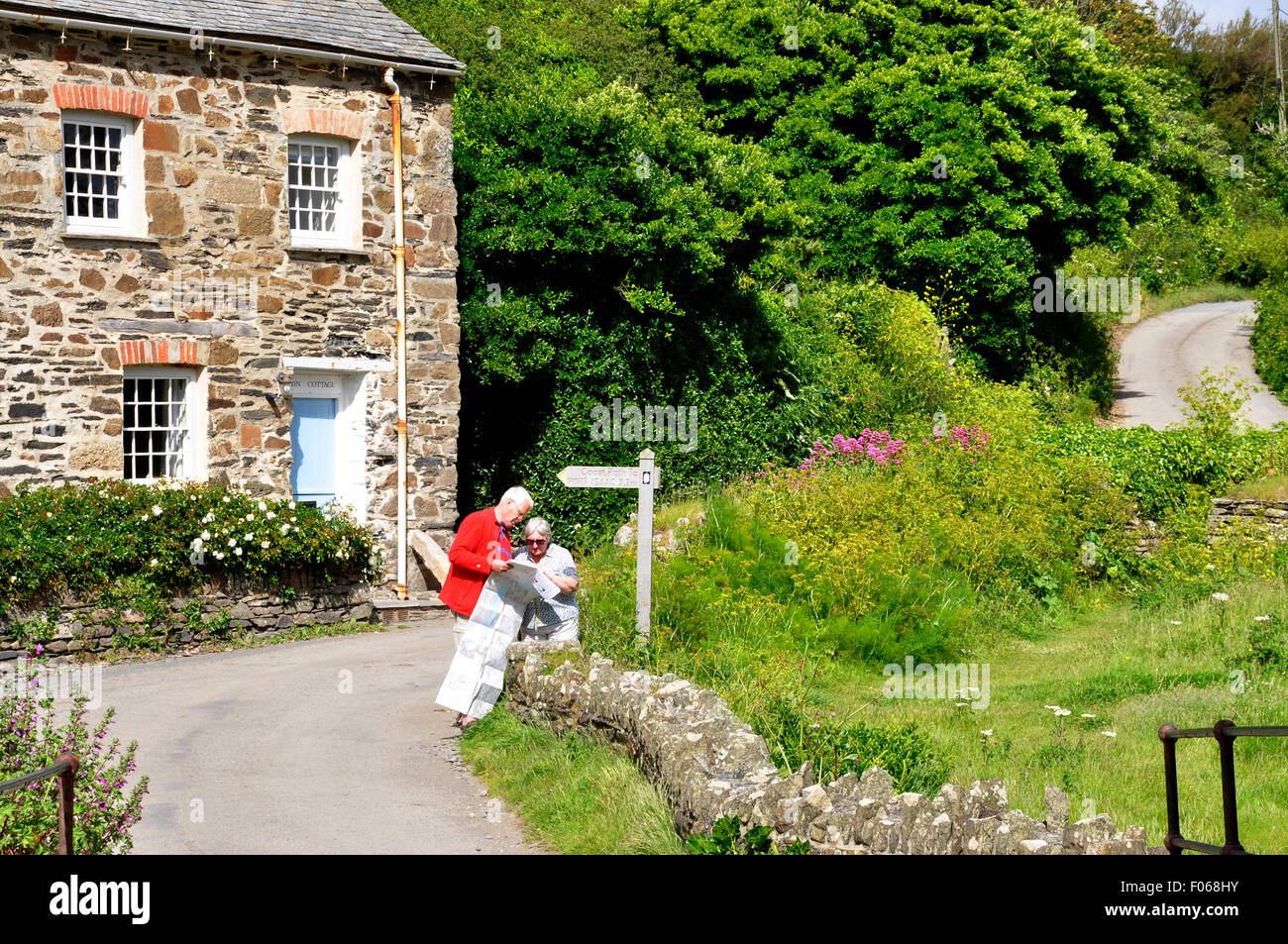 Ennesima Cornwall - paese di avvolgimento lane - dito post - giovane guardando una mappa - cottage vicino da - prato - muro di pietra - la luce del sole Foto Stock