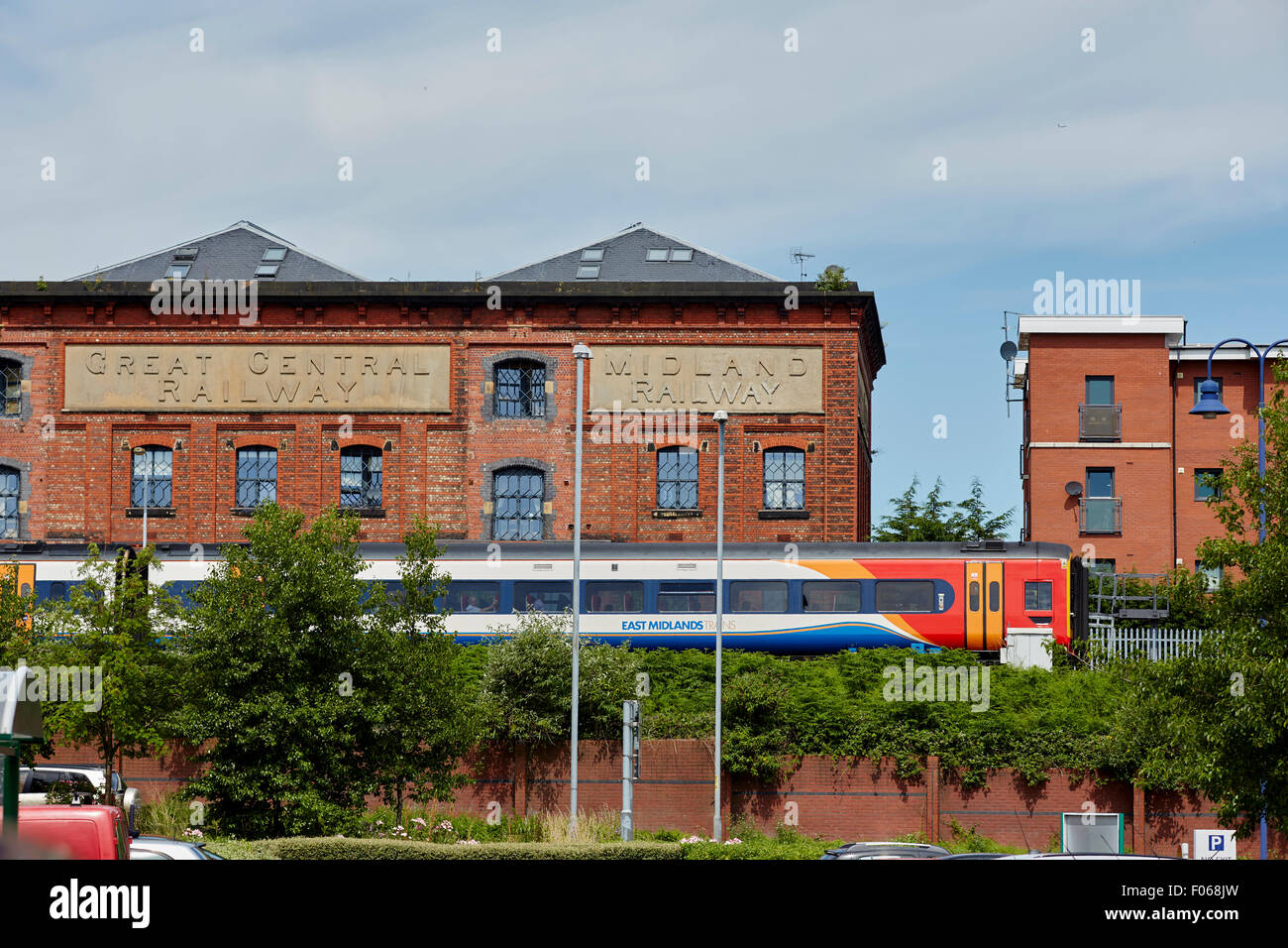 Dmu locale treno passeggeri a warrington central passando di vecchi magazzini Foto Stock