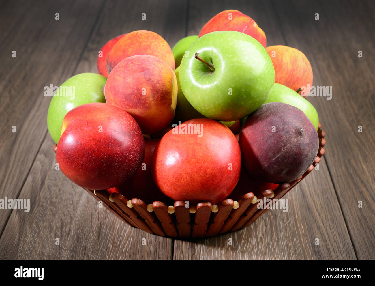 Pesche fresche e mele nel cesto su un tavolo di legno Foto Stock