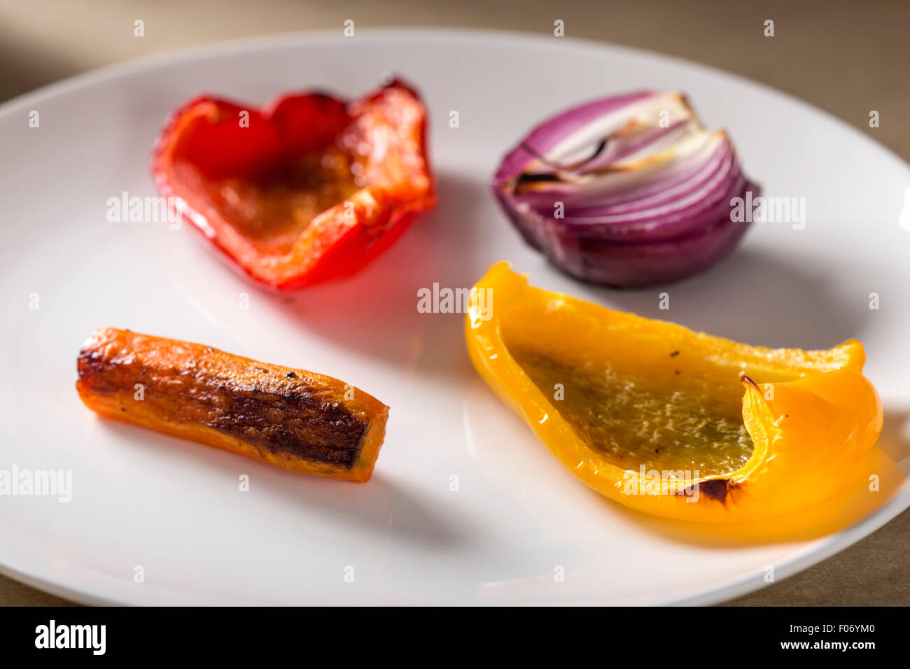 Verdure arrosto su un bianco piatto di portata. Carote, cipolle rosse, rosso e giallo pepe Foto Stock