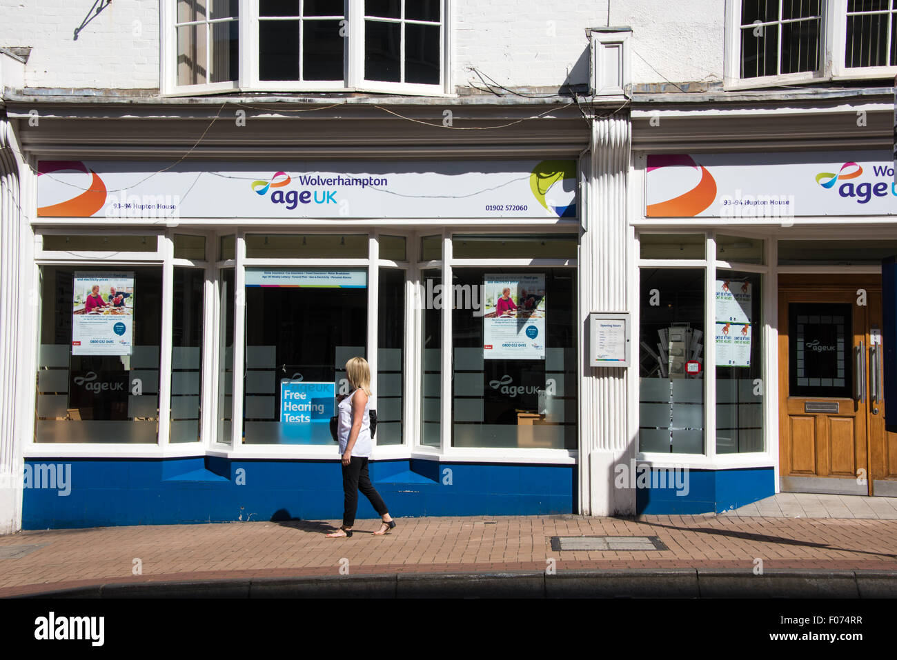 Una donna che cammina oltre l'età UK shop on high street Wolverhampton West Midlands, Regno Unito Foto Stock