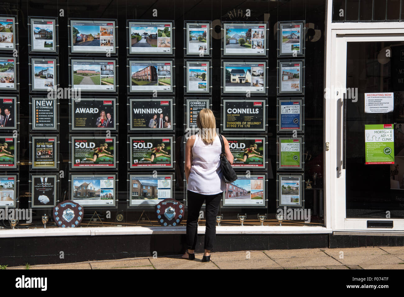Una donna che guarda nella finestra di Agenti immobiliari su high street Wolverhampton West Midlands, Regno Unito Foto Stock