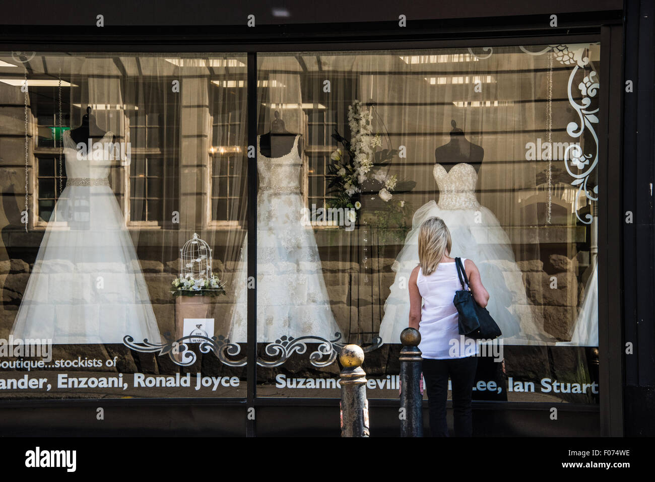 Una donna che guarda attraverso la finestra in abito nuziale in un negozio nuziale su high street Wolverhampton West Midlands, Regno Unito Foto Stock