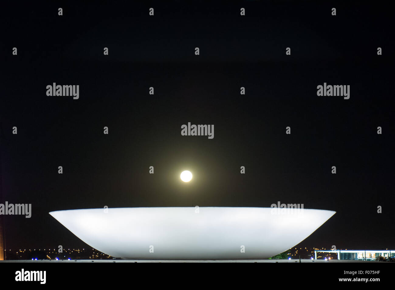 Brasilia DF, Brasile. Congresso Nazionale di edifici da parte dell'architetto Oscar Niemeyer; il piatto di notte con la luna piena a basso su di esso. Praça dos Tres Poderes. Foto Stock