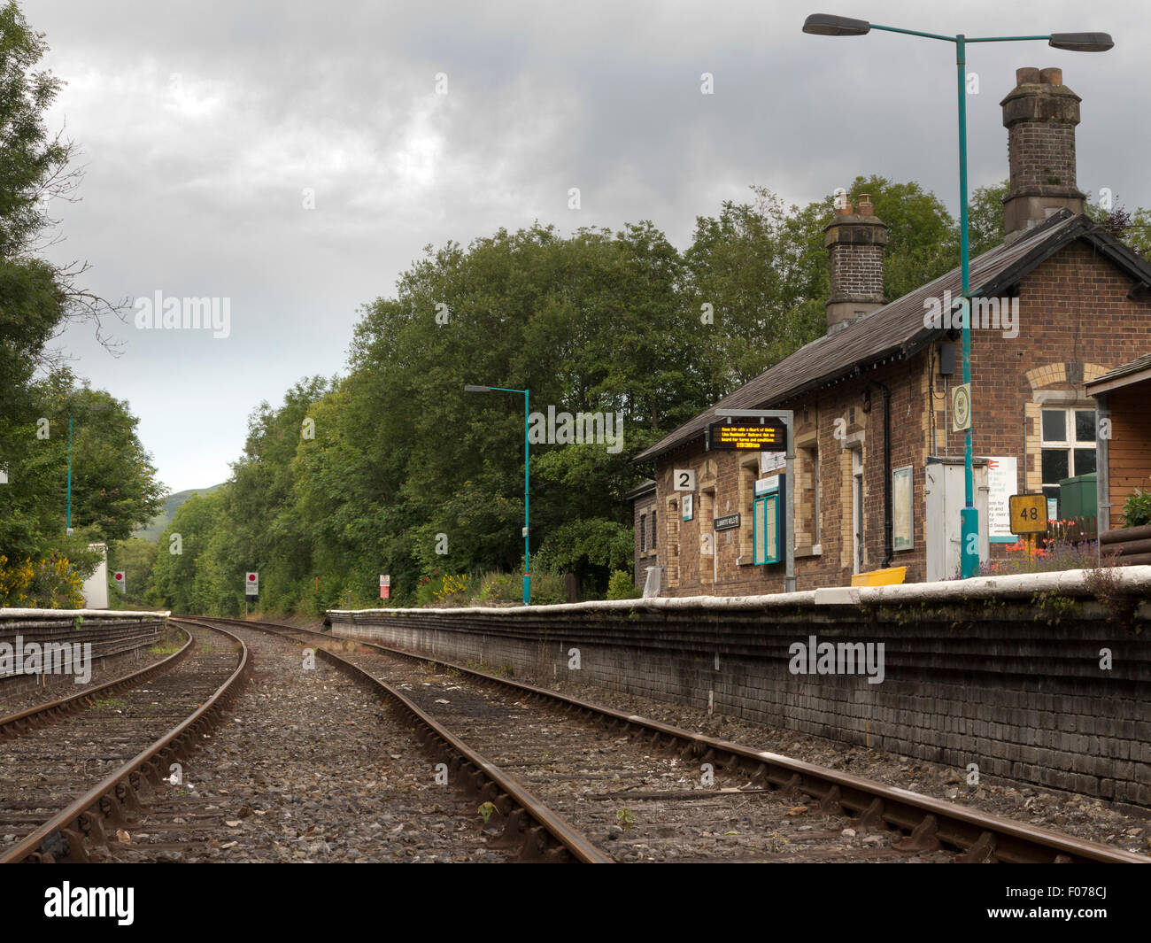 Vista da via del cielo nuvoloso oltre il deserta stazione ferroviaria a Llanwrtyd Wells, Powys, il Galles Centrale Foto Stock