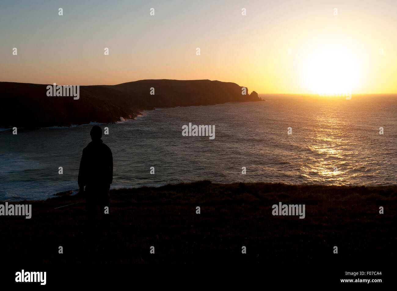 Un viandante sulla rupe sopra la baia Kearvaig al tramonto, sulla costa nord est di Cape Wrath, Sutherland, Scotland, Regno Unito. Foto Stock