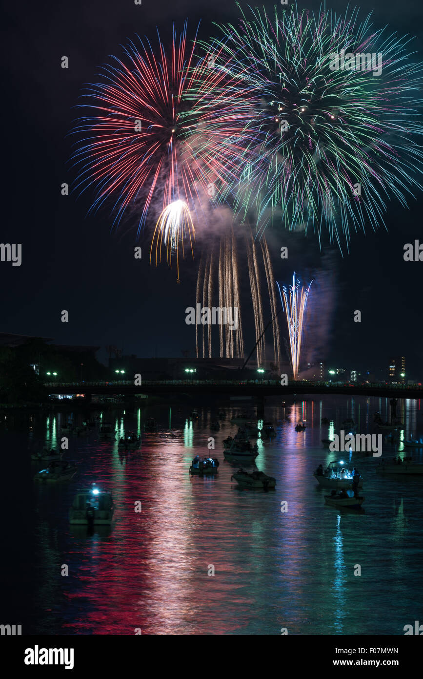 Coloratissimi fuochi d'artificio riflessa in un fiume con molte piccole barche e un paesaggio urbano lungo il fianco nella campagna di Kochi, Giappone. Foto Stock