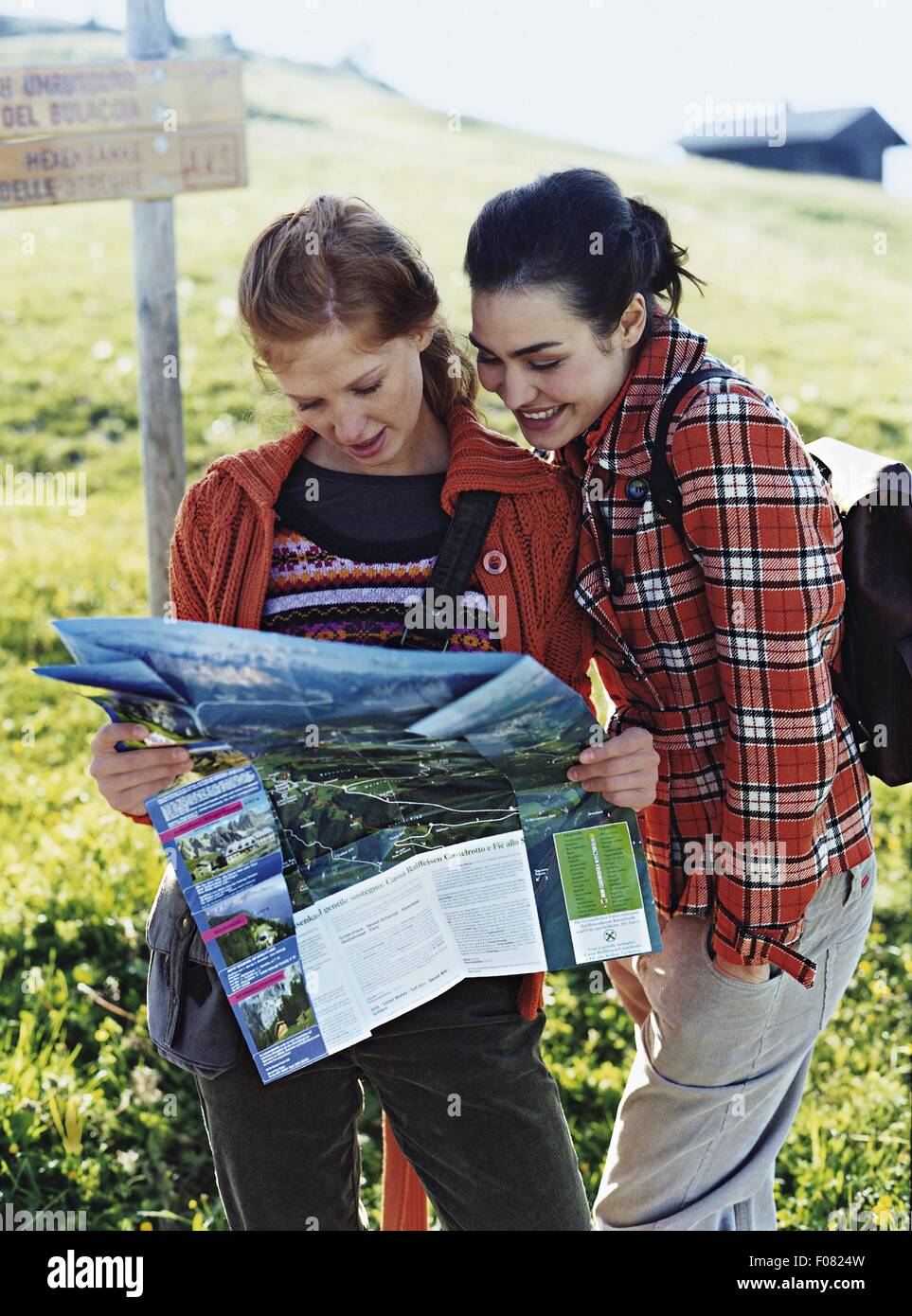 Due donna indossando giacca autunno guardando la guida illustrata mappa e sorridente Foto Stock