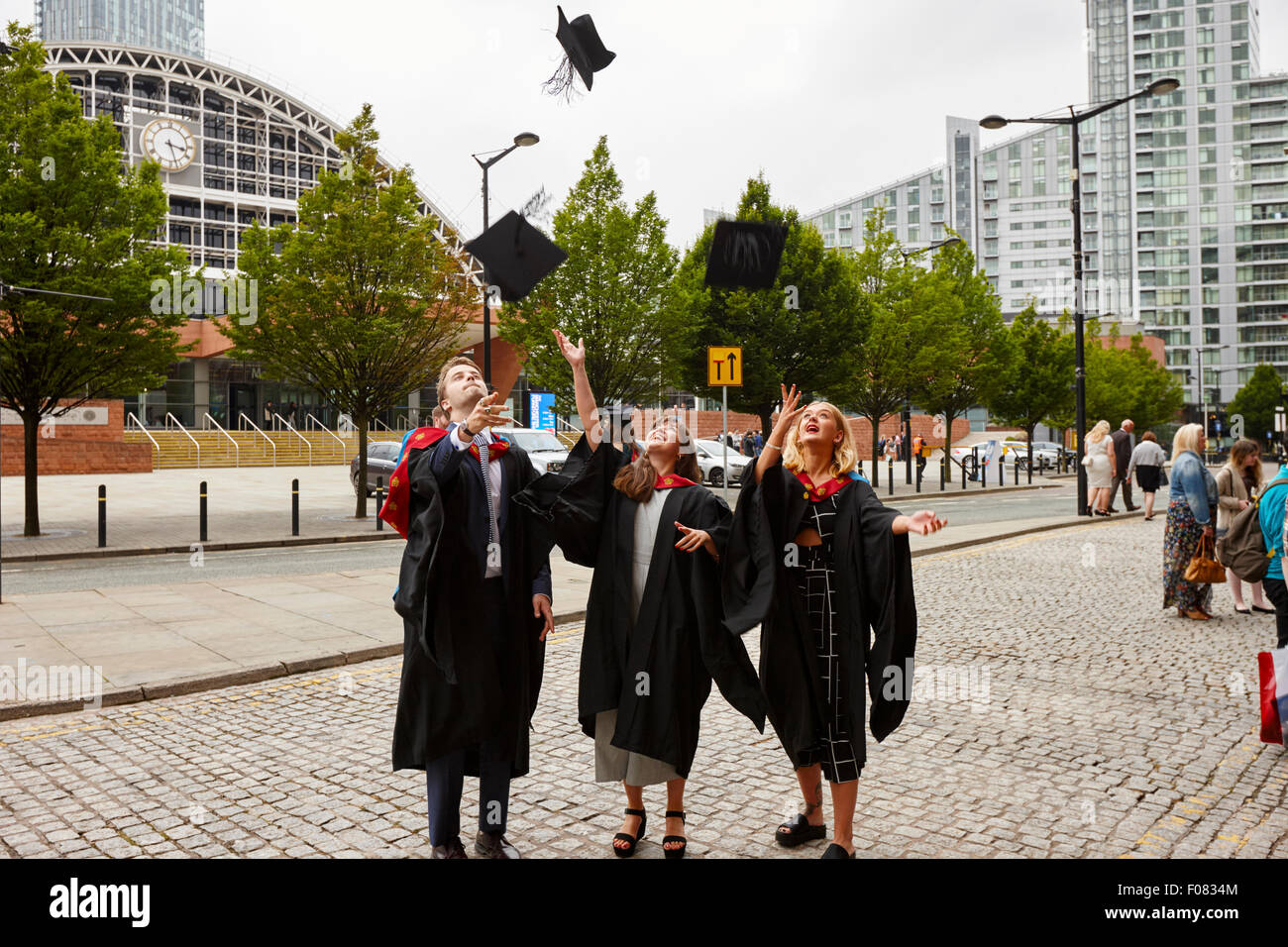 I laureati di gettare la scheda di mortaio cappelli in aria dopo la cerimonia di laurea in Manchester Inghilterra England Regno Unito Foto Stock