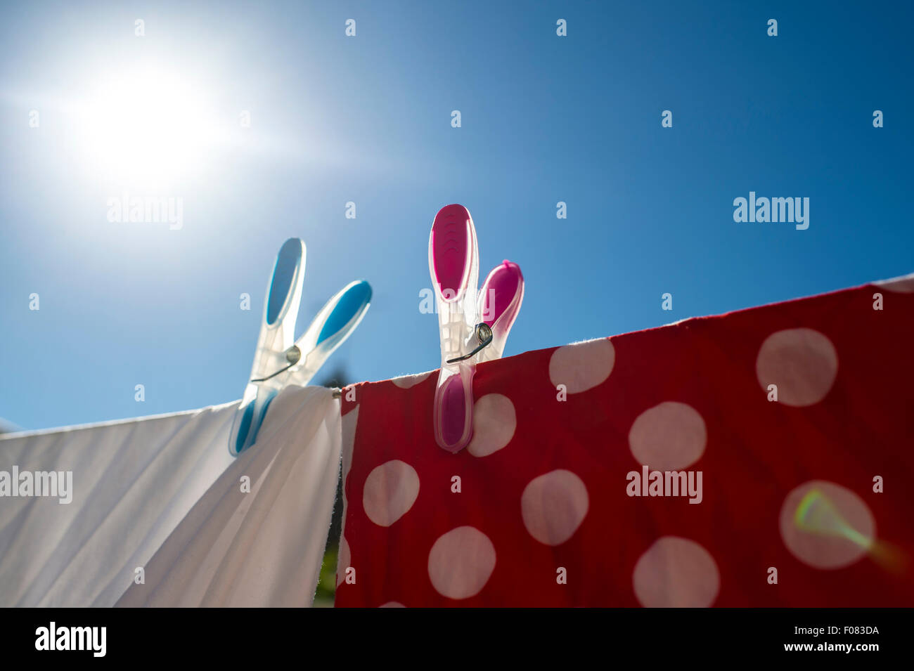 Il bianco e il rosso servizio lavanderia essiccazione al sole ancorato sulla linea di lavaggio con pioli colorati. Foto Stock