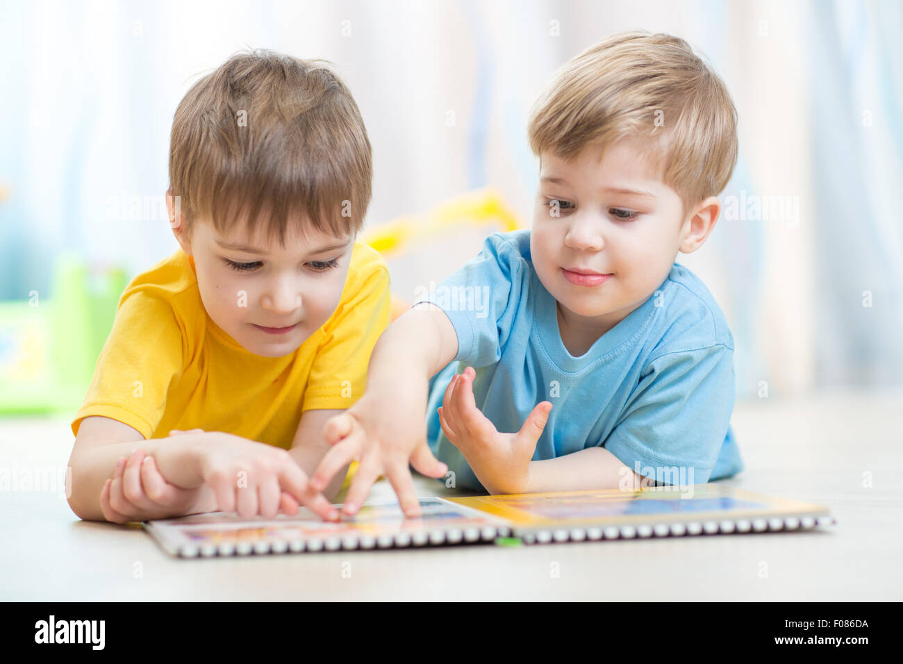 Splendidi bambini a leggere un libro sul pavimento a casa Foto Stock