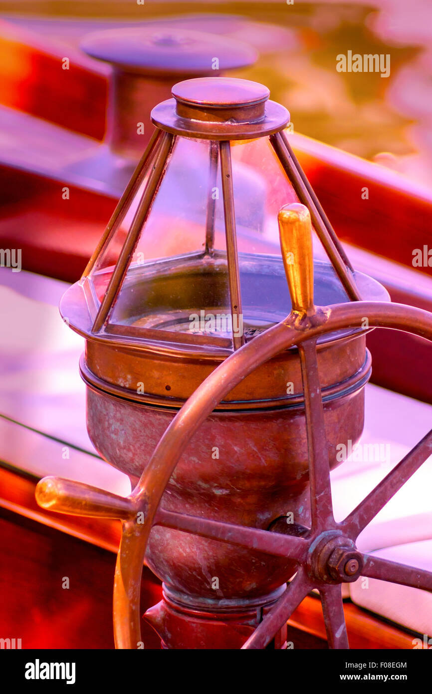 Un antico bussola e volante a dominare questa fotografia nautico dall'interno della cabina di pilotaggio di un vintage in barca a vela. Foto Stock