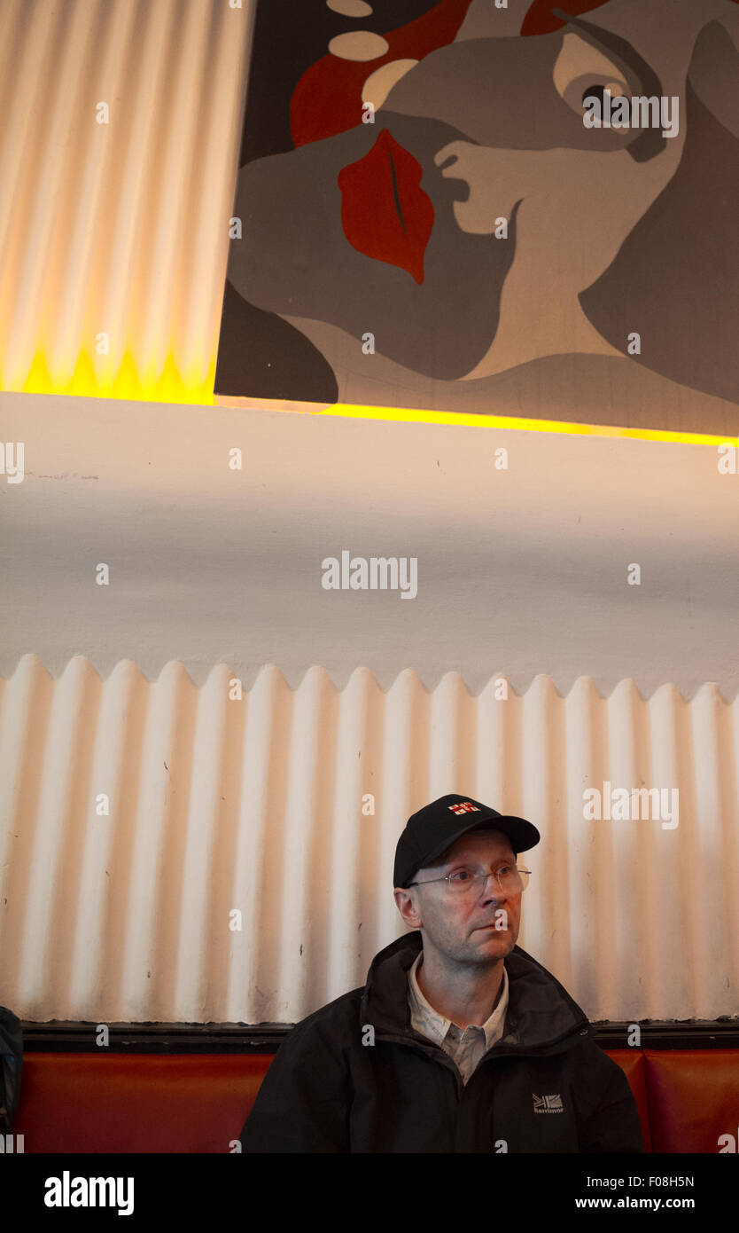 Uomo seduto in un bar con una femmina di pittura modernista guardando verso il basso. Foto Stock Uomo seduto in un bar con una femmina di pittura modernista guardando verso il basso. Foto Stock