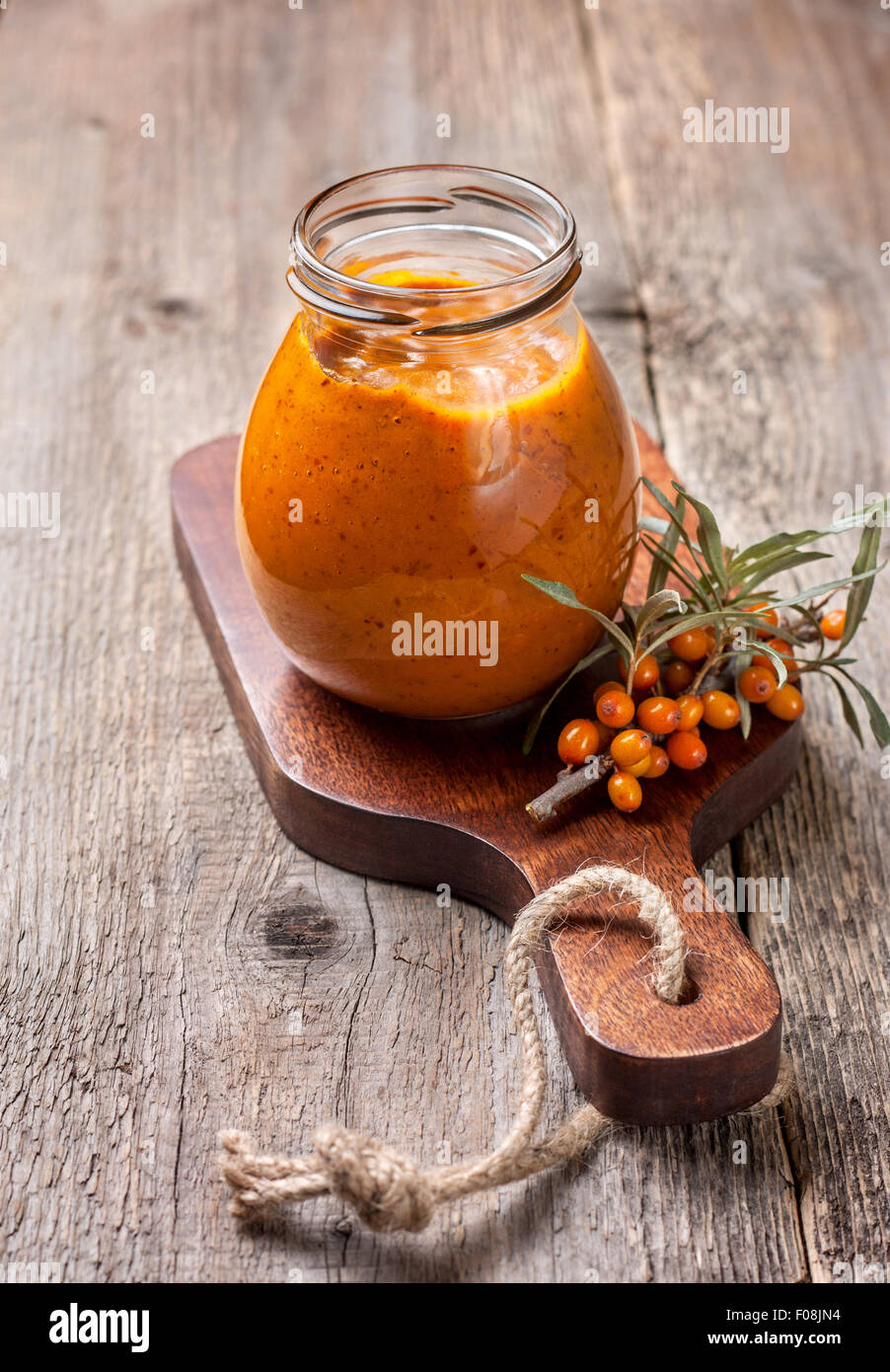 Vaso di vetro con bacche di olivello spinoso jam su uno sfondo di legno Foto Stock