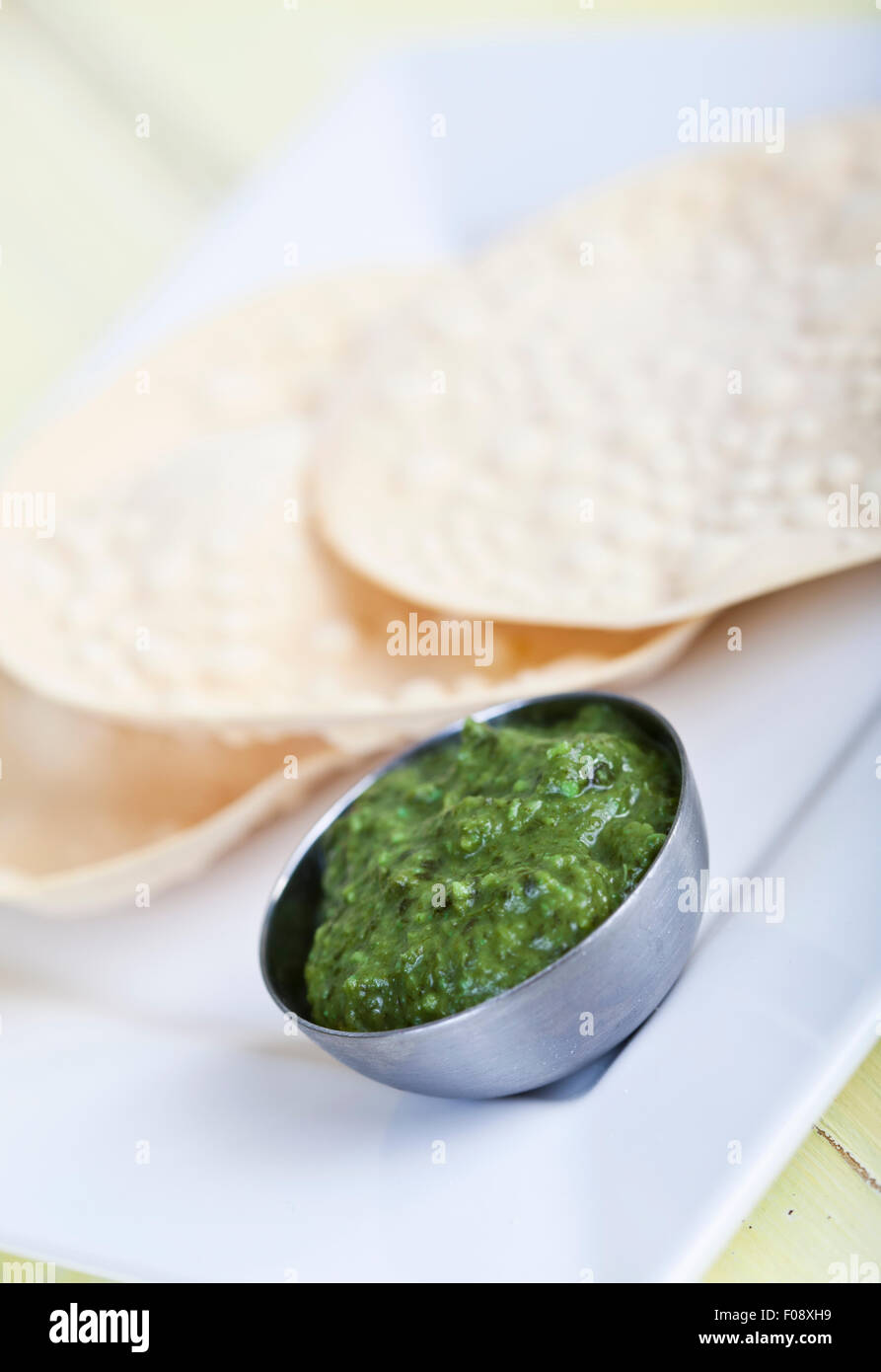 Un mucchio di poppadoms con una ciotola di chutney corriander Foto Stock