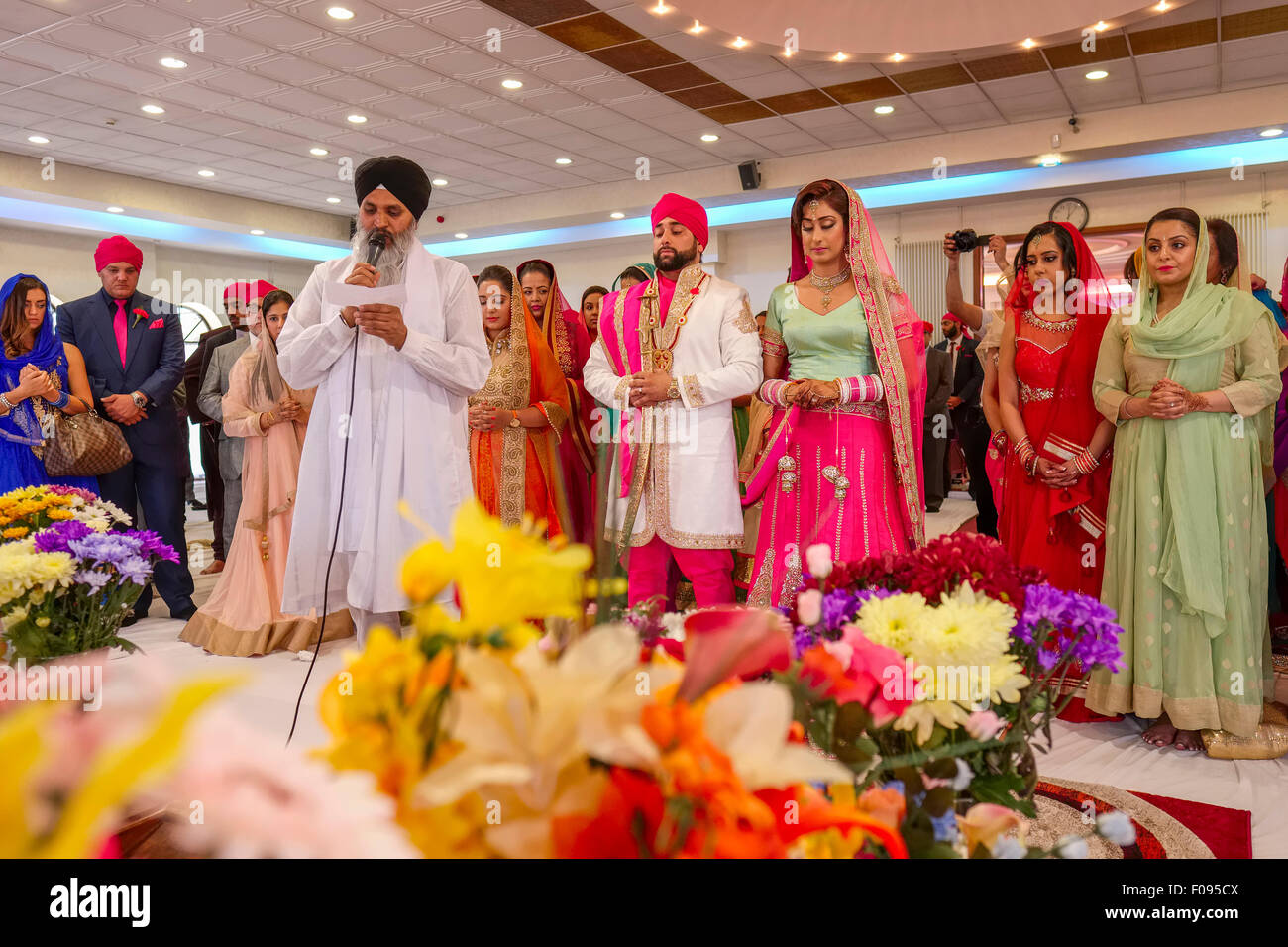 Sacerdote con la sposa e lo sposo a Sikh cerimonia di nozze in Brent Gurdwara Londra Foto Stock