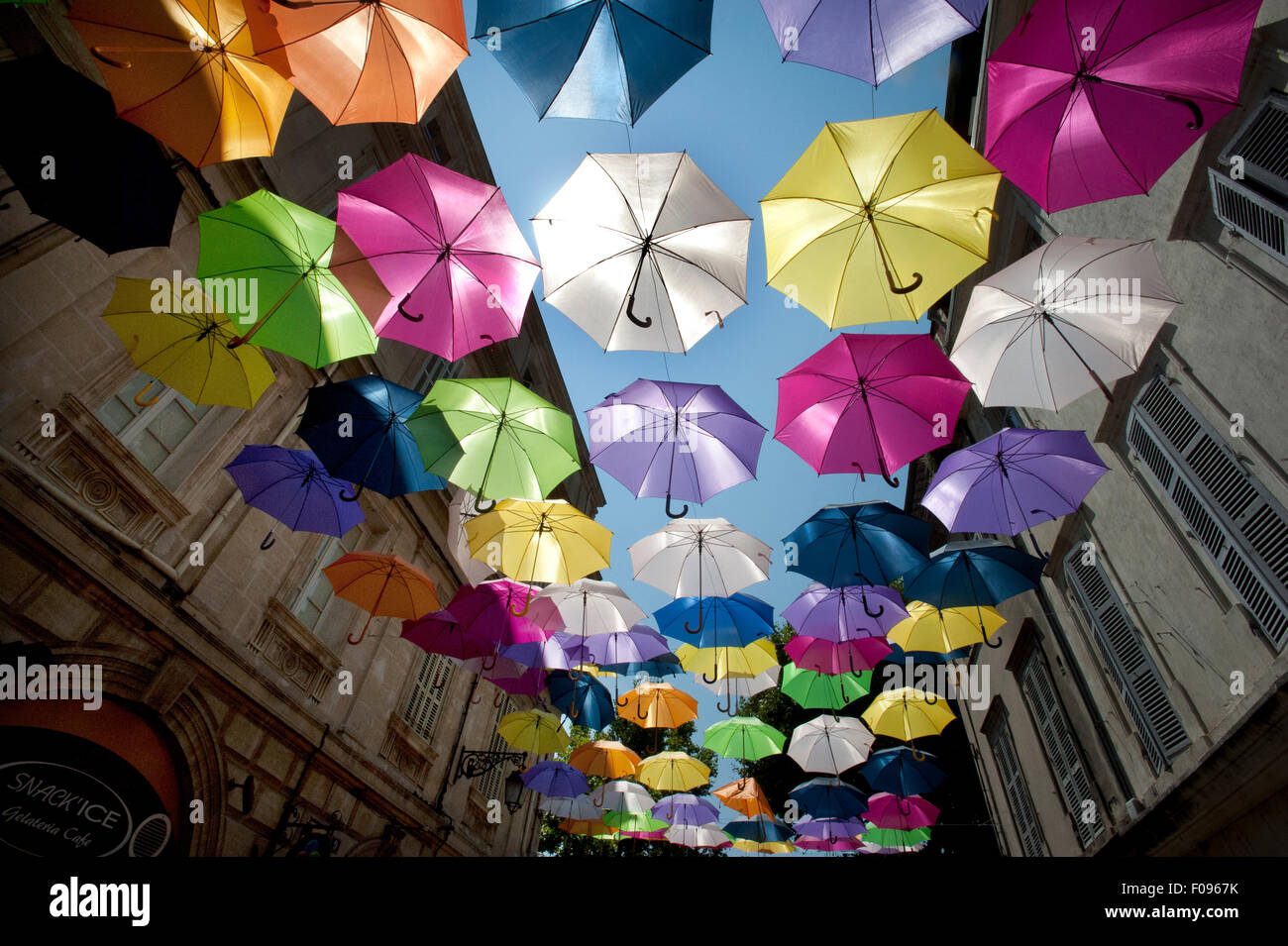 Un mare di Colorati luminosamente floating ombrelloni riempire il cielo sopra la Rue Jean Jaures in Arles, Provenza, sud della Francia. Foto Stock