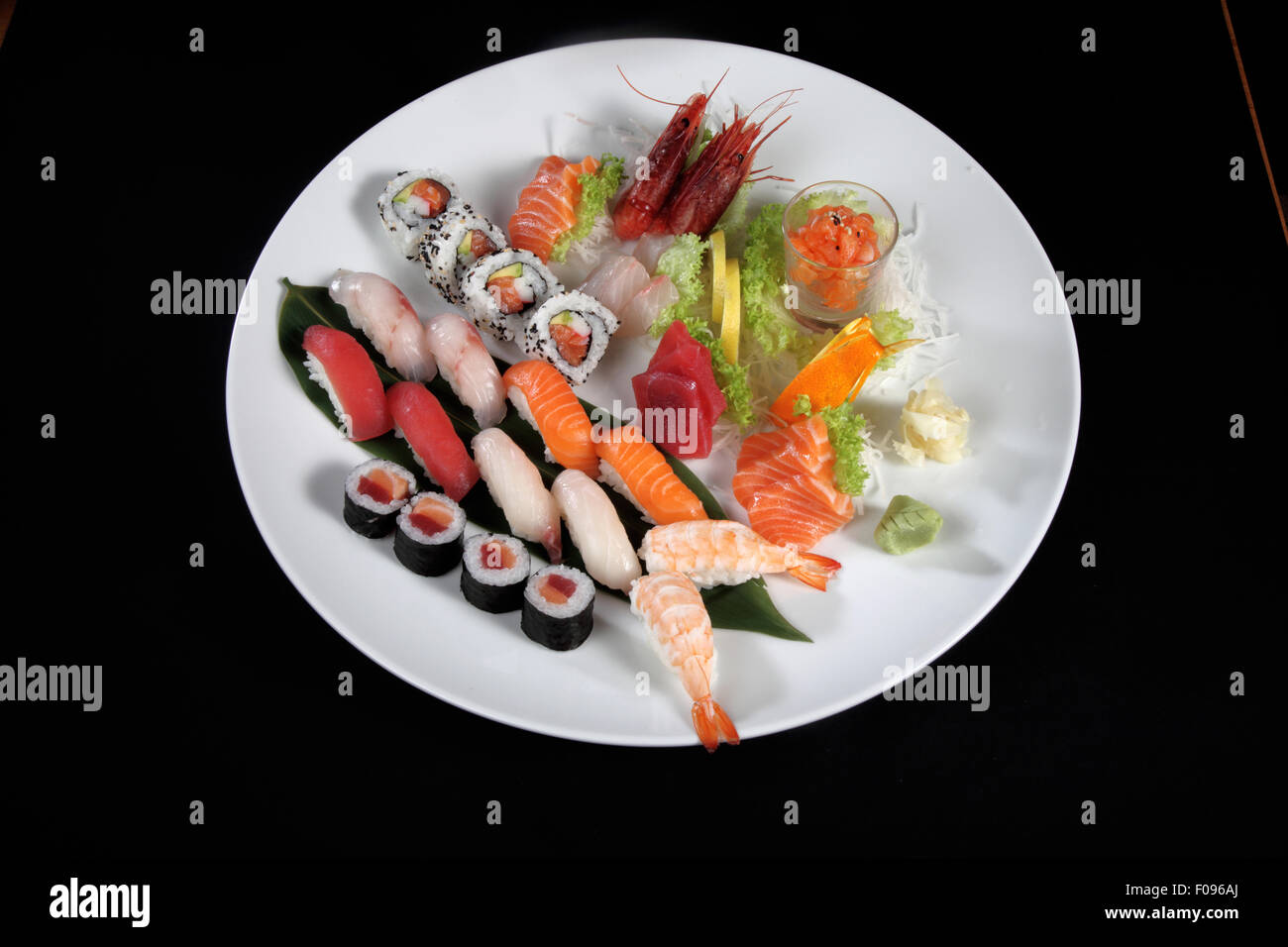 Piastra rotonda di sushi e sashimi su sfondo nero Foto Stock