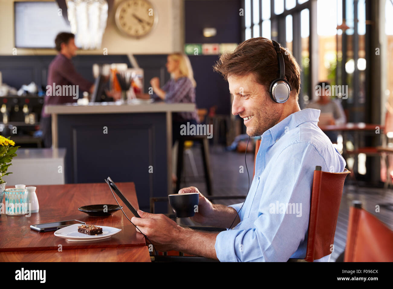 Uomo con tavoletta digitale in un coffee shop Foto Stock